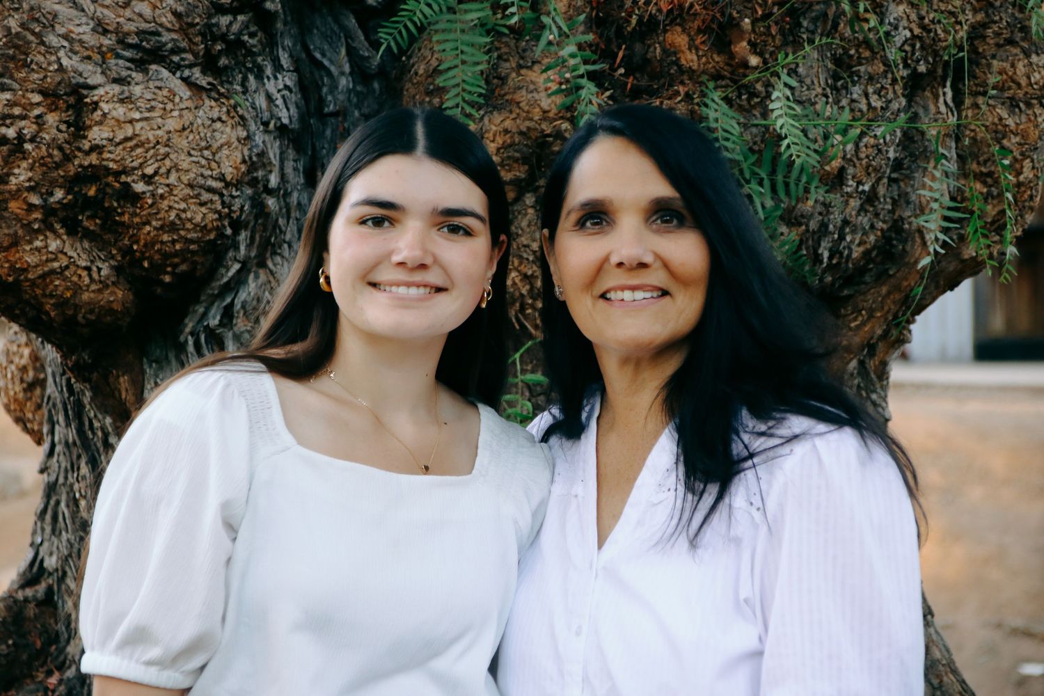 Family portrait session in white outfits against natural outdoor backdrop.