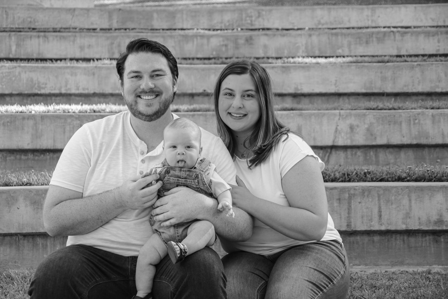 Family photo session on wooden steps with casual attire and natural expressions.