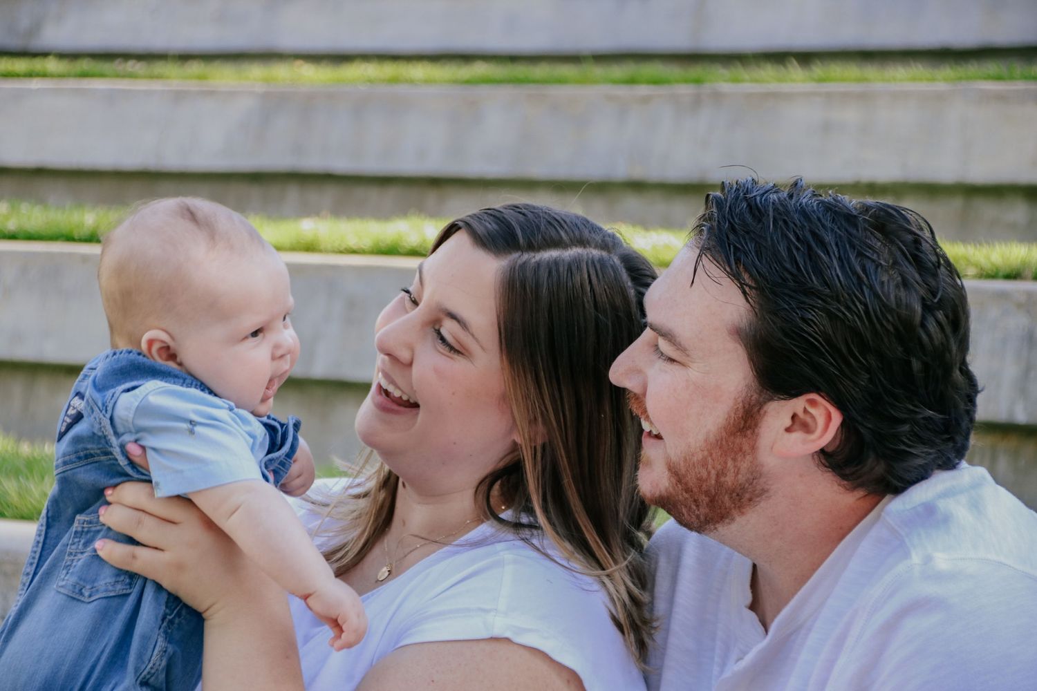 Family shares joyful outdoor moments together while sitting on steps in matching white clothing.