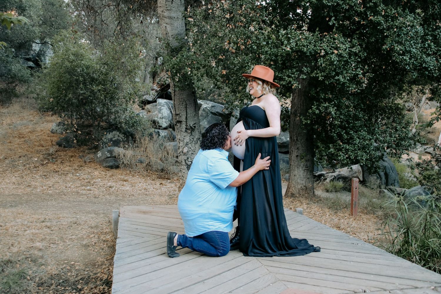 Two people share an intimate moment on a wooden walkway amidst a rocky natural landscape.
