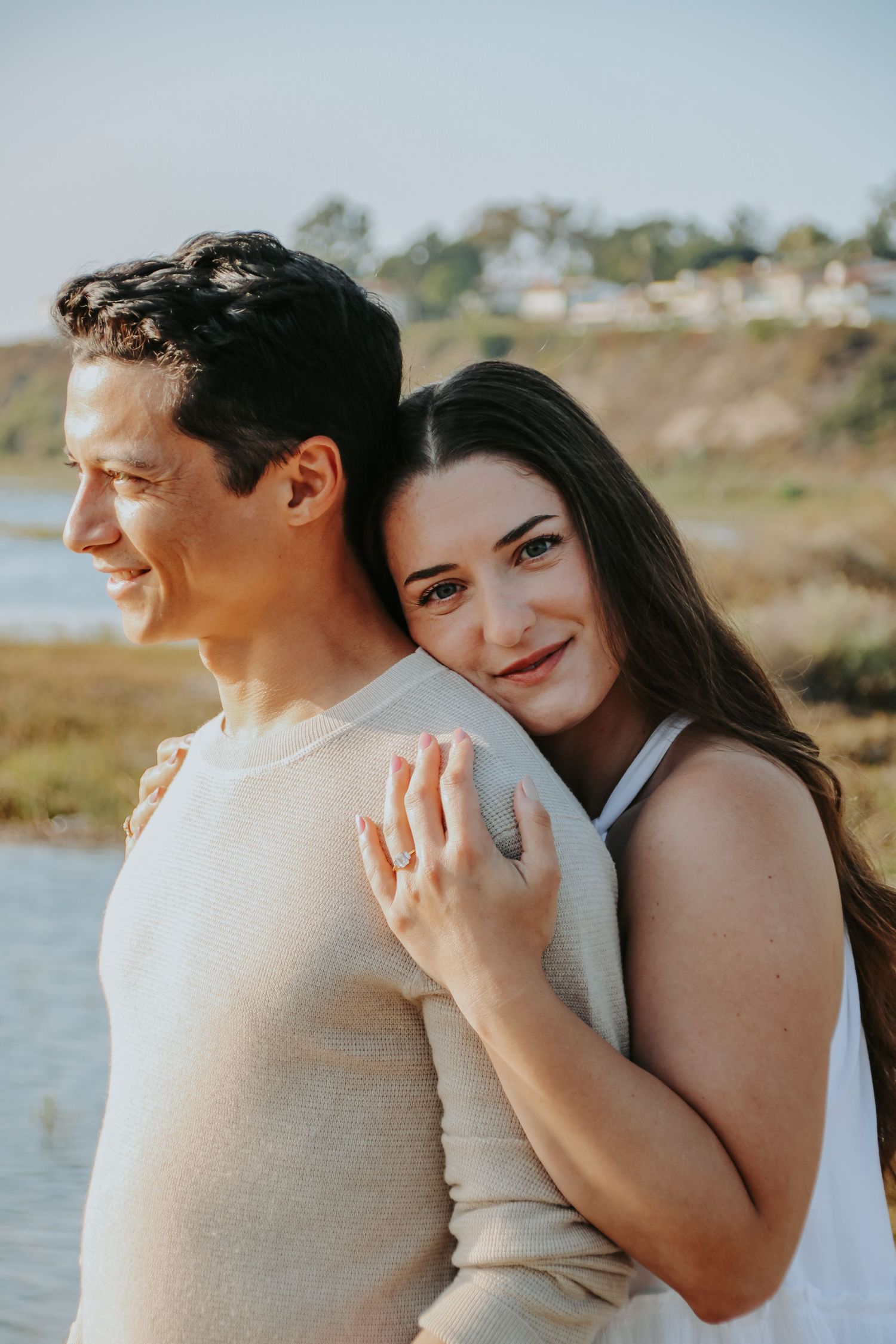 Couple shares tender embrace during seaside photoshoot at golden hour.