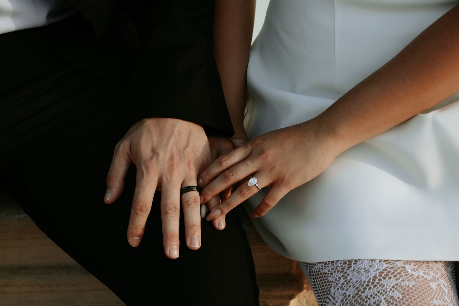 Intimate black and white photographs focusing on hands and wedding dress details.