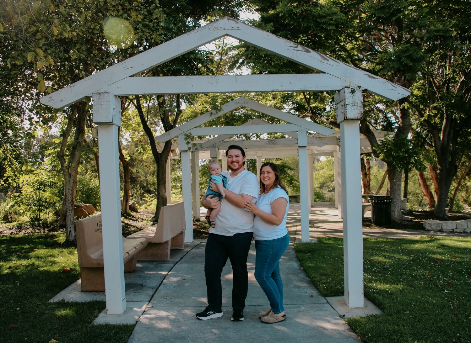 Family standing under white garden gazebo for outdoor portrait session.