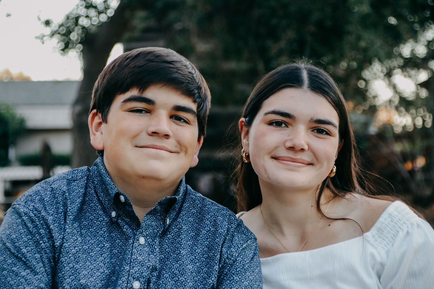 Close up photo of two people sharing genuine smiles while sitting outdoors.