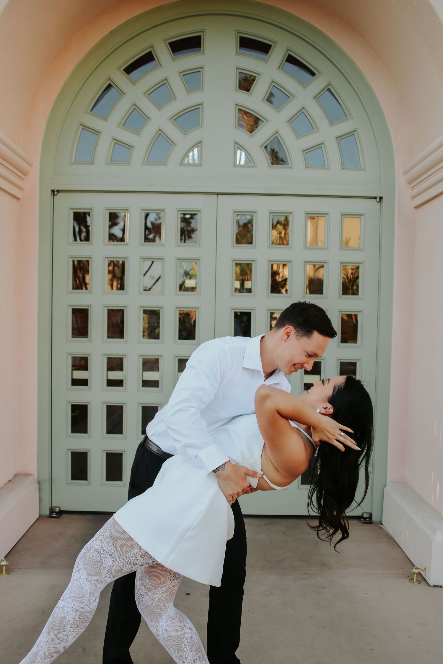 Couple performing a dramatic dance dip pose against a decorative arched doorway backdrop.