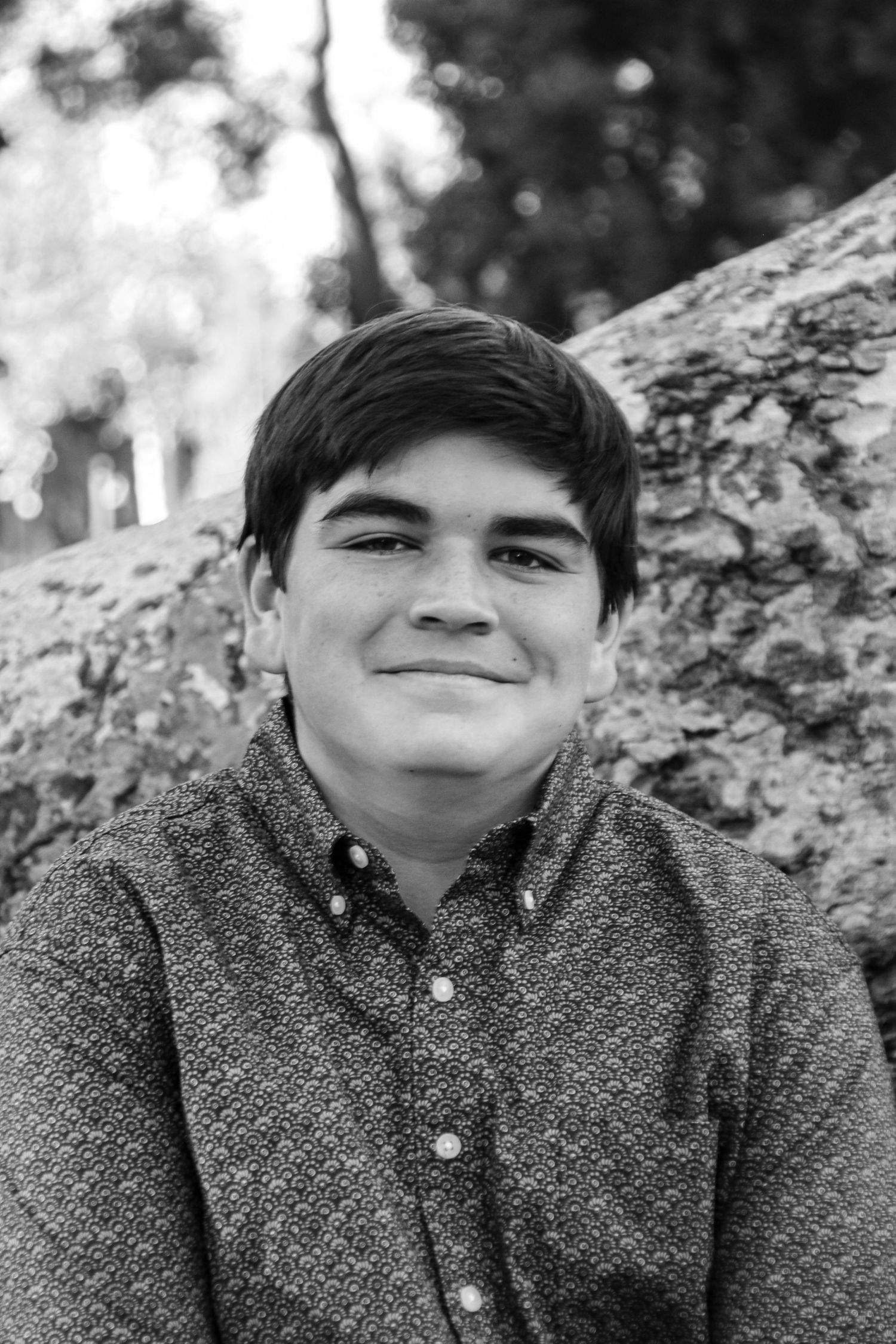 Black and white close-up portrait showing youthful expression against textured background.