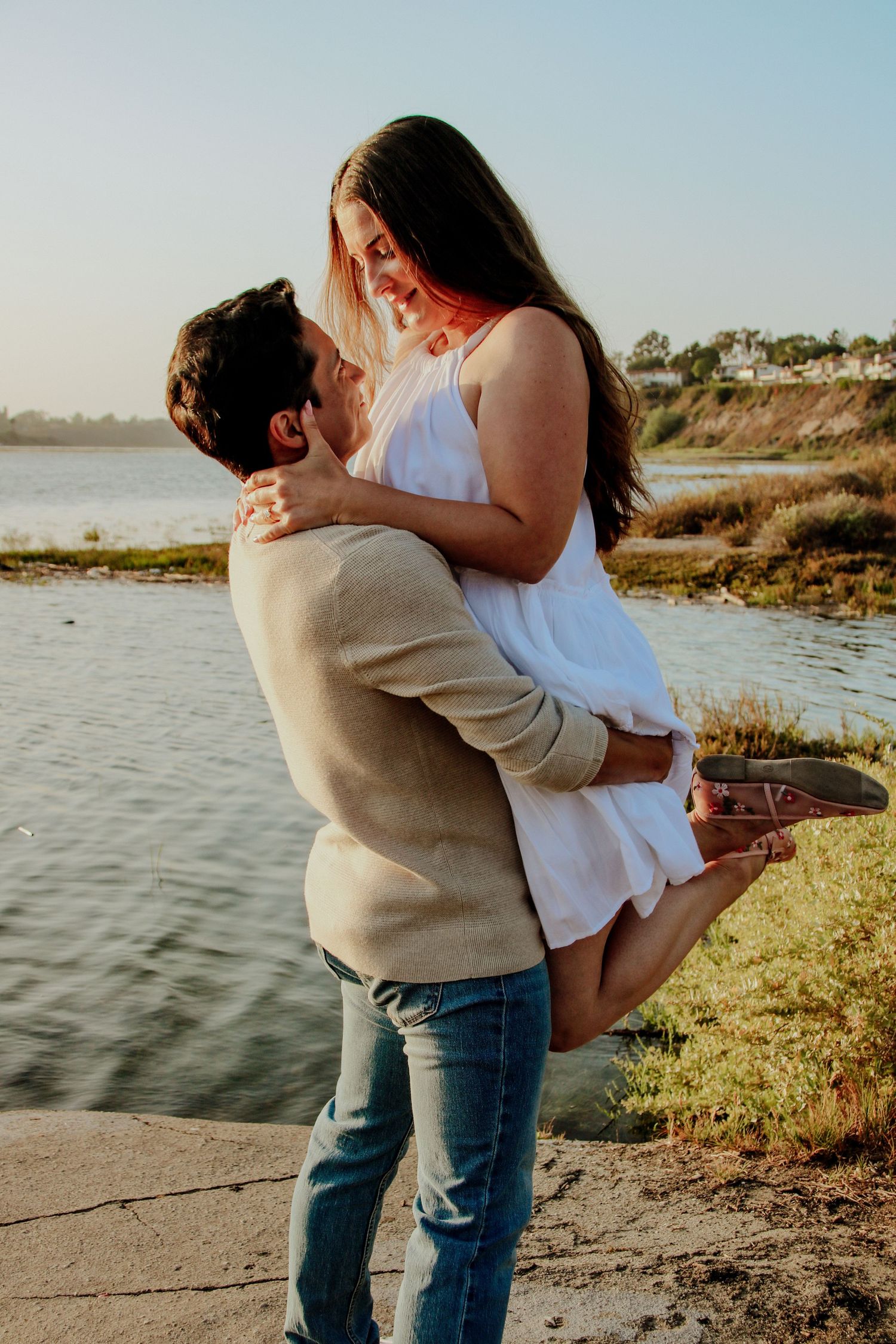 A romantic moment shared between a couple at a scenic waterfront location.