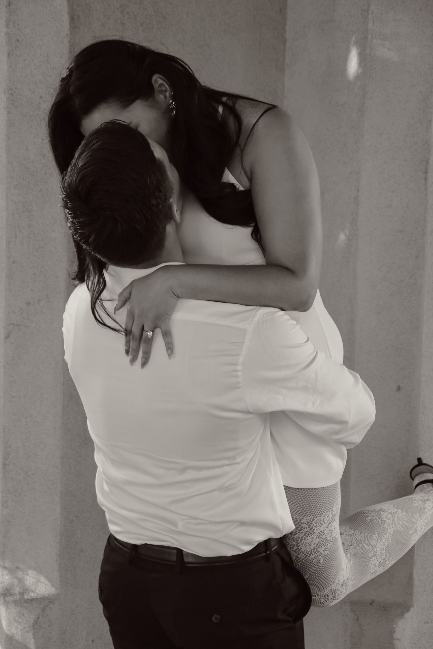 A couple in contrasting outfits embracing closely in an intimate moment.