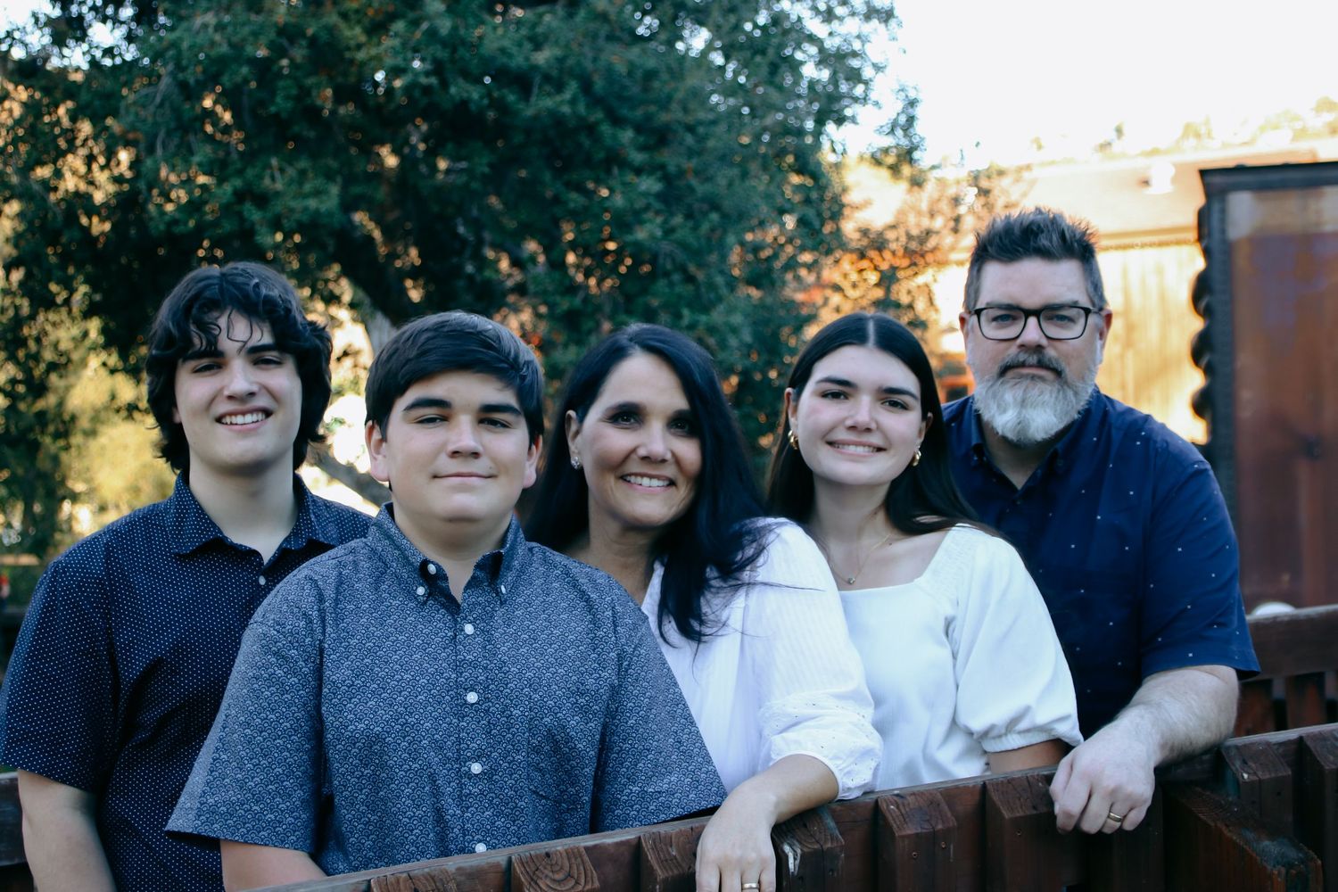 Family gathering posed together against a natural backdrop with trees.