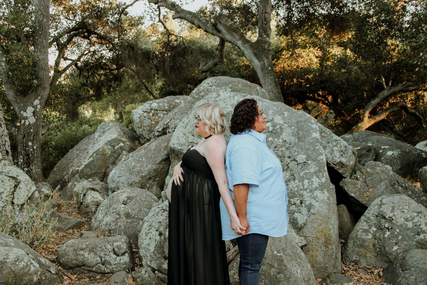 A couple enjoys a sunset moment together among large boulders in a natural outdoor setting.