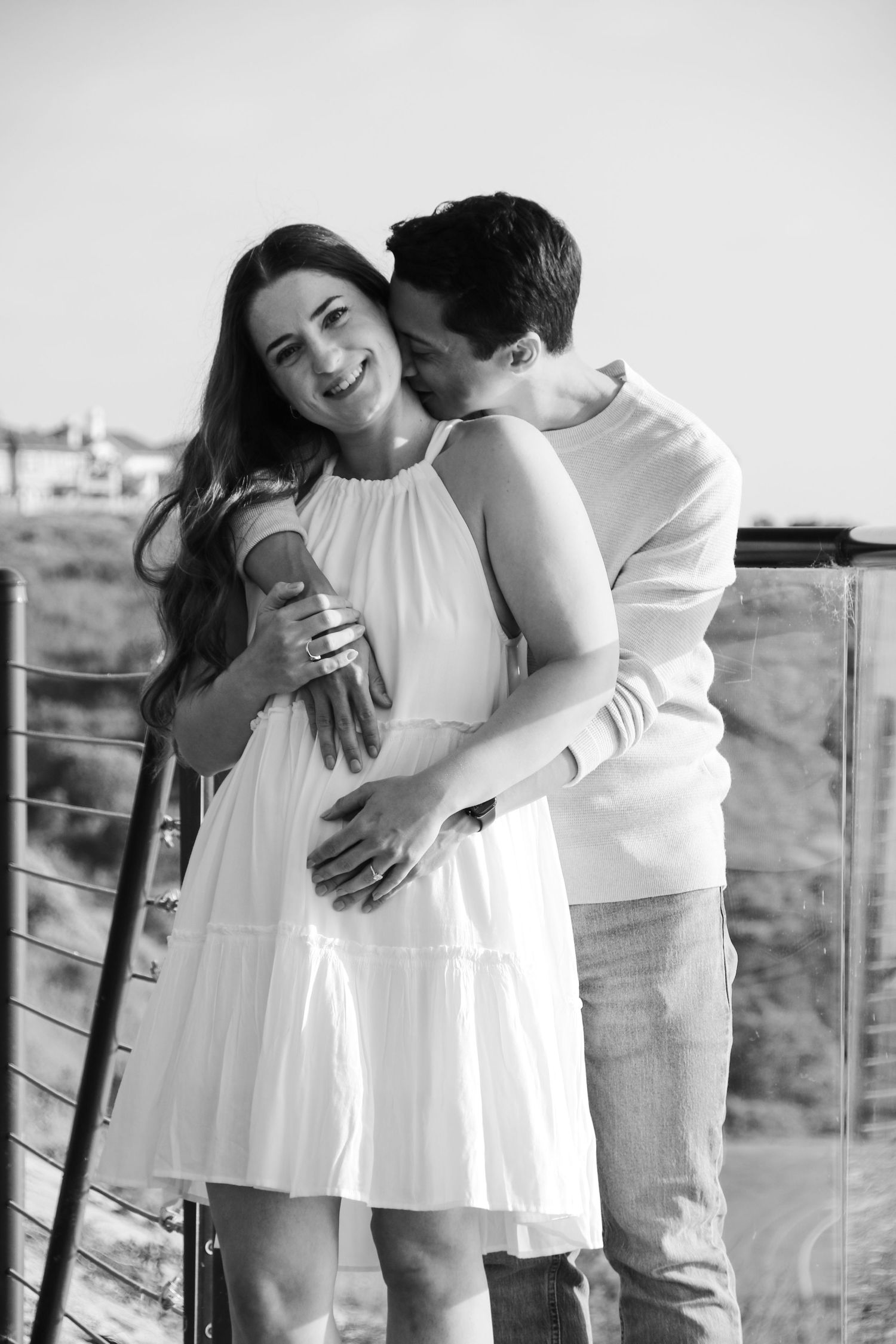 Black and white romantic photos of couple sharing intimate moments on scenic overlook.