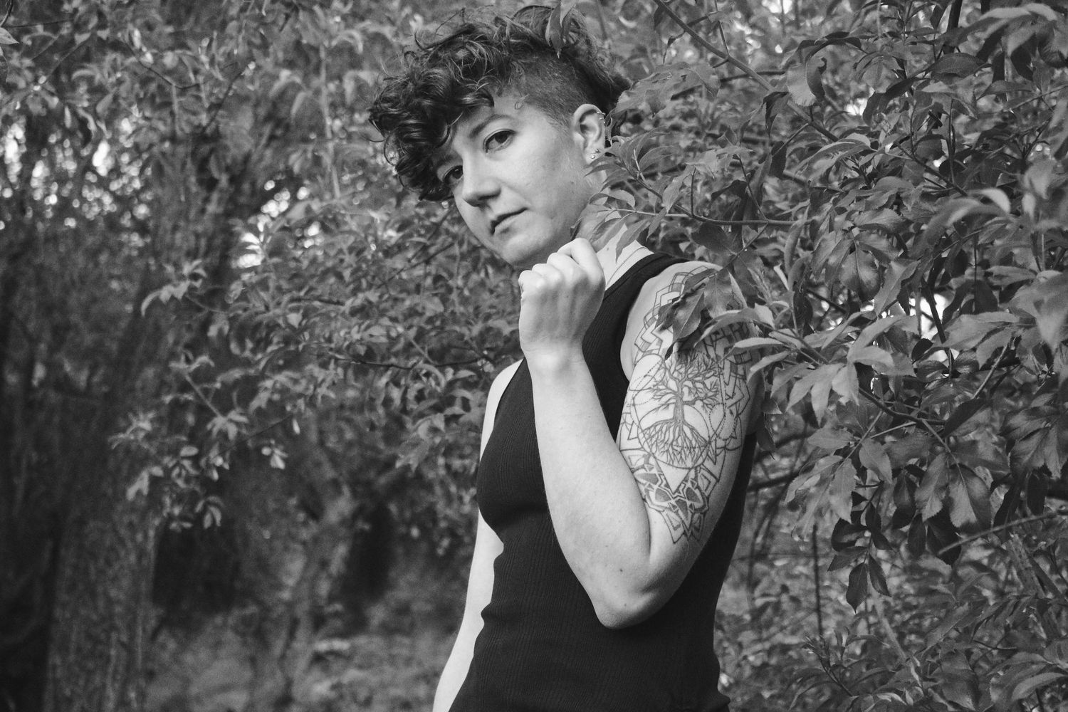 Artistic black and white portrait showing person in sleeveless top surrounded by nature.