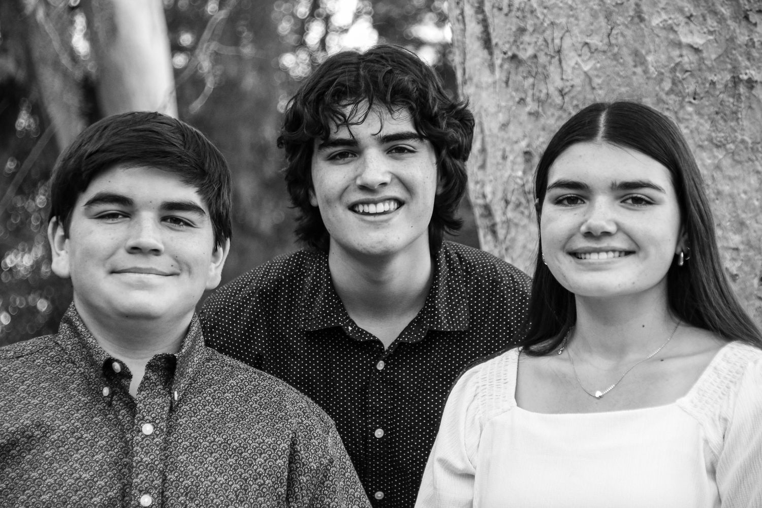 Black and white portrait series of three people smiling at the camera.