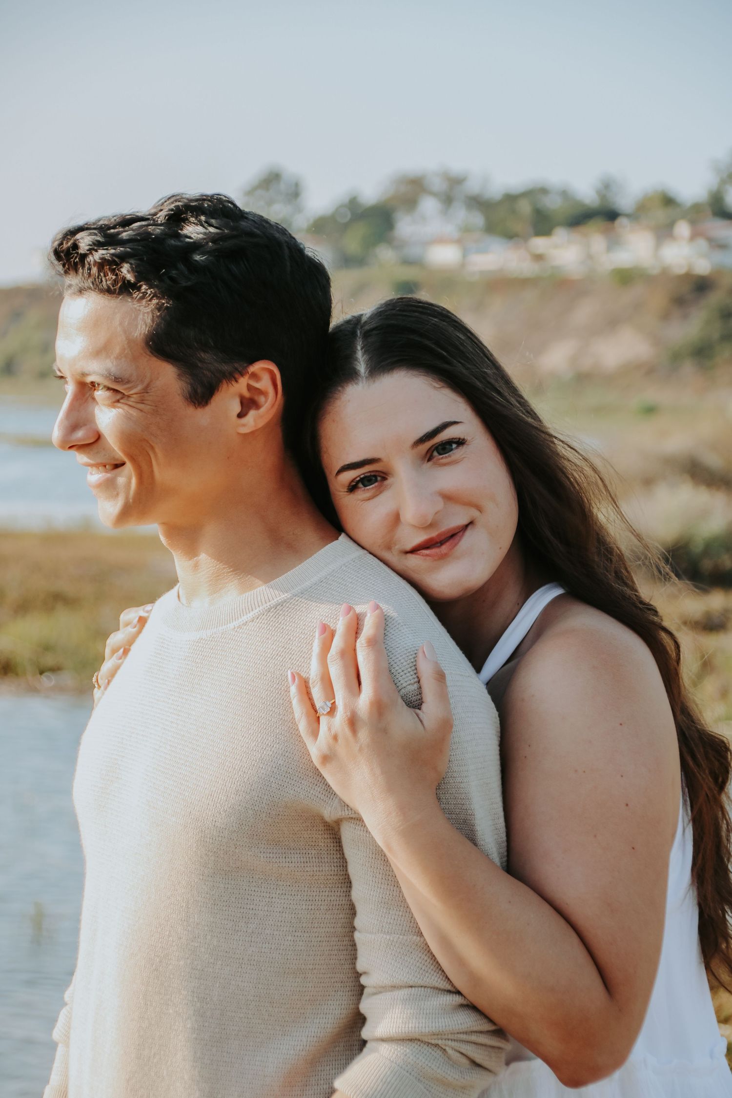 Sweet couple portrait with natural coastal scenery and warm sunset lighting.