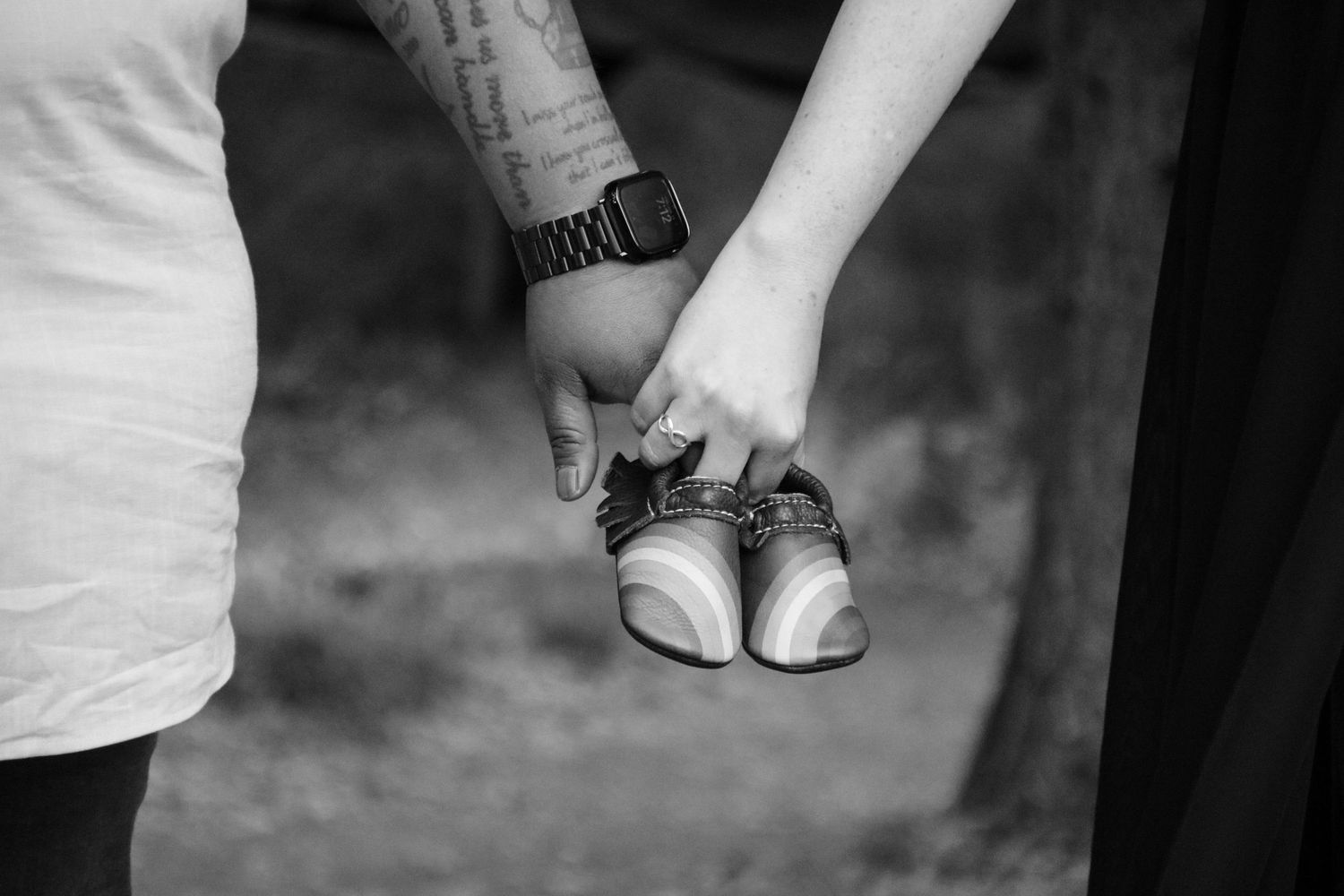 Black and white artistic detail shot of hands against a neutral backdrop.