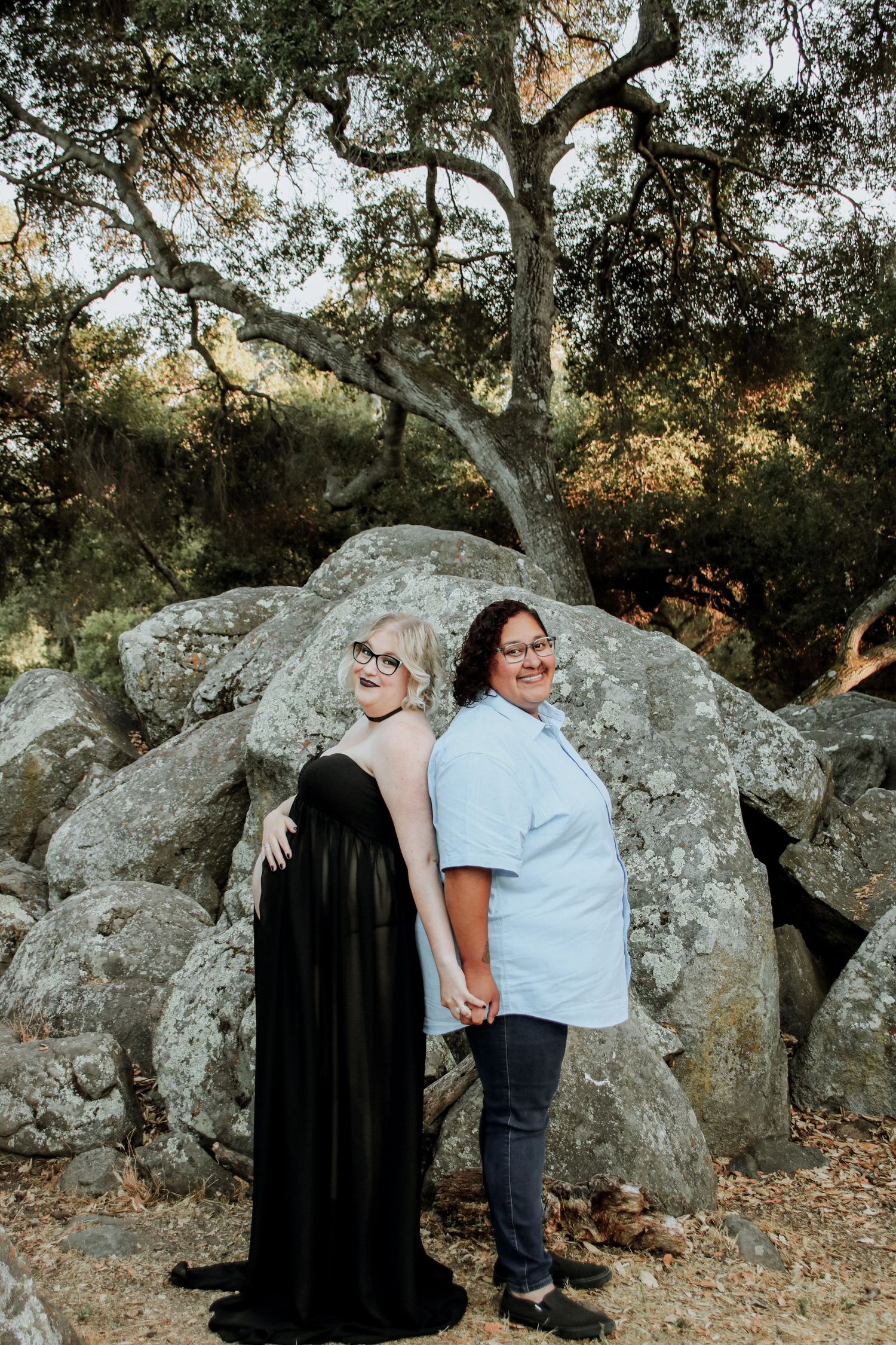 People enjoying a tender moment in front of weathered rocks and gnarled oak trees.