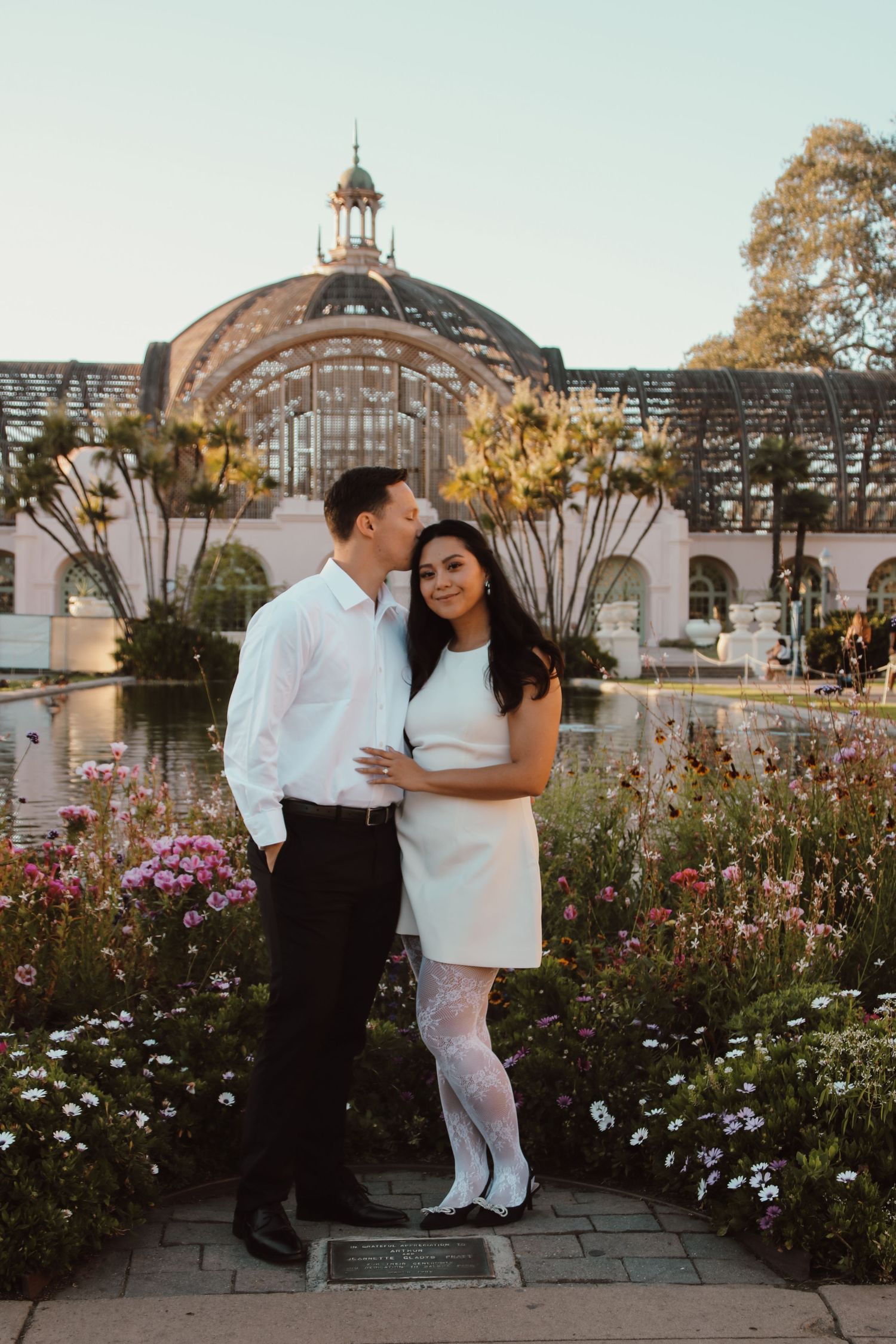 Romantic photo series in a flower garden with ornate architectural backdrop.