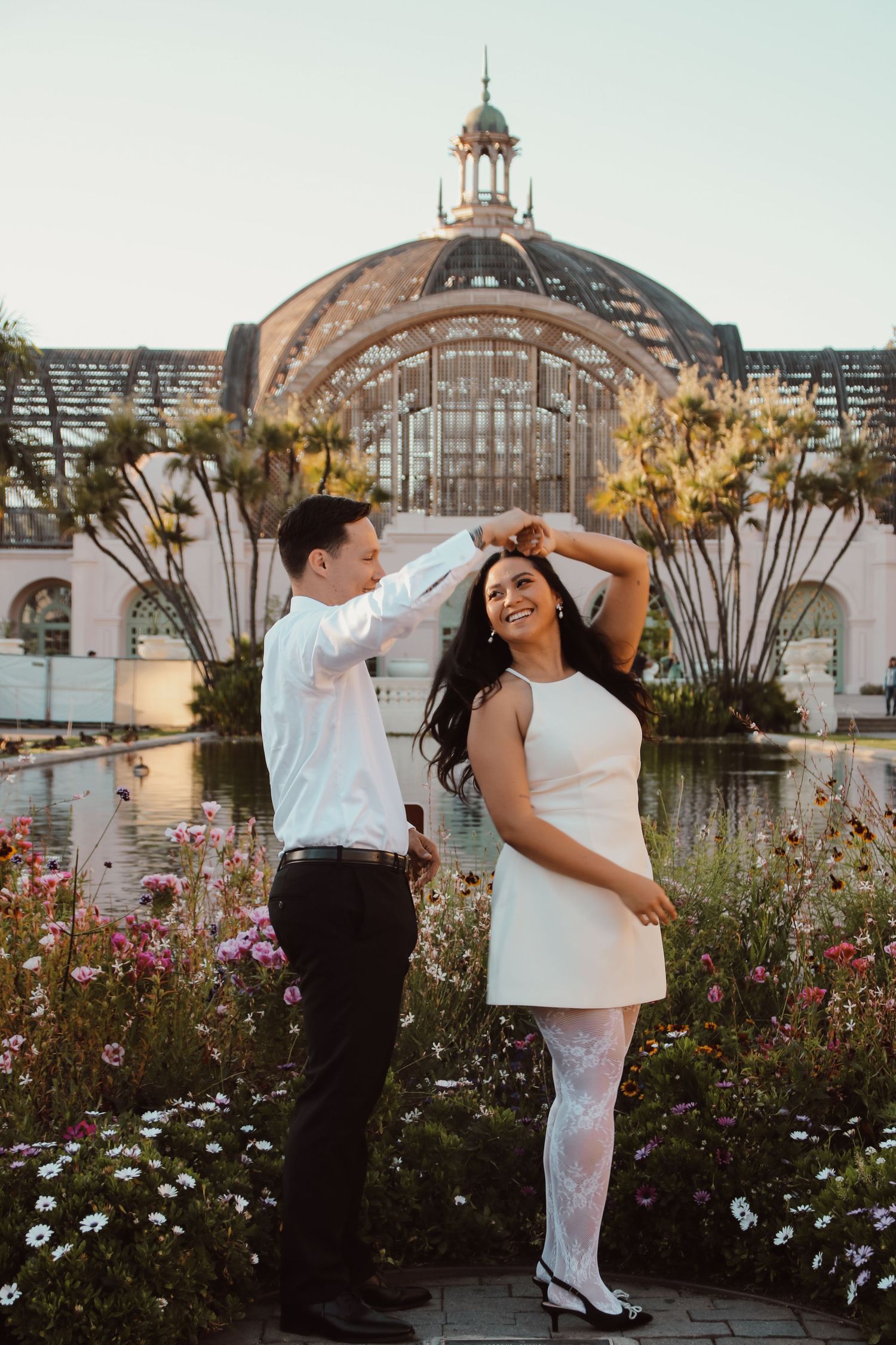 A spirited dance pose photographed before a magnificent glass-domed building with reflecting pools.