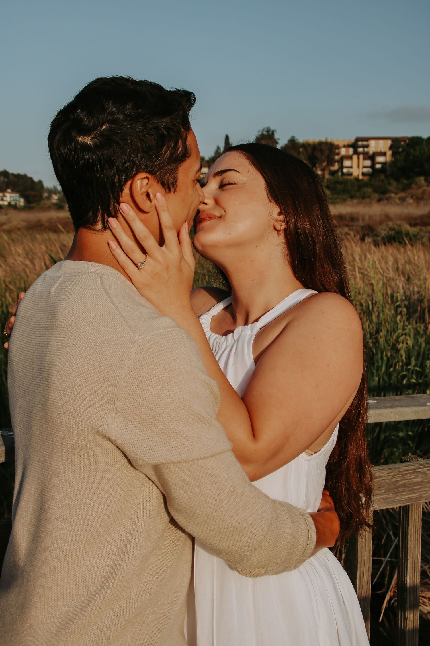 Intimate golden hour portrait of couple sharing a tender moment on outdoor deck.