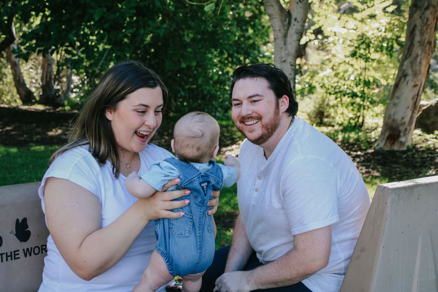 Family laughing together during casual outdoor photo session with natural backdrop.