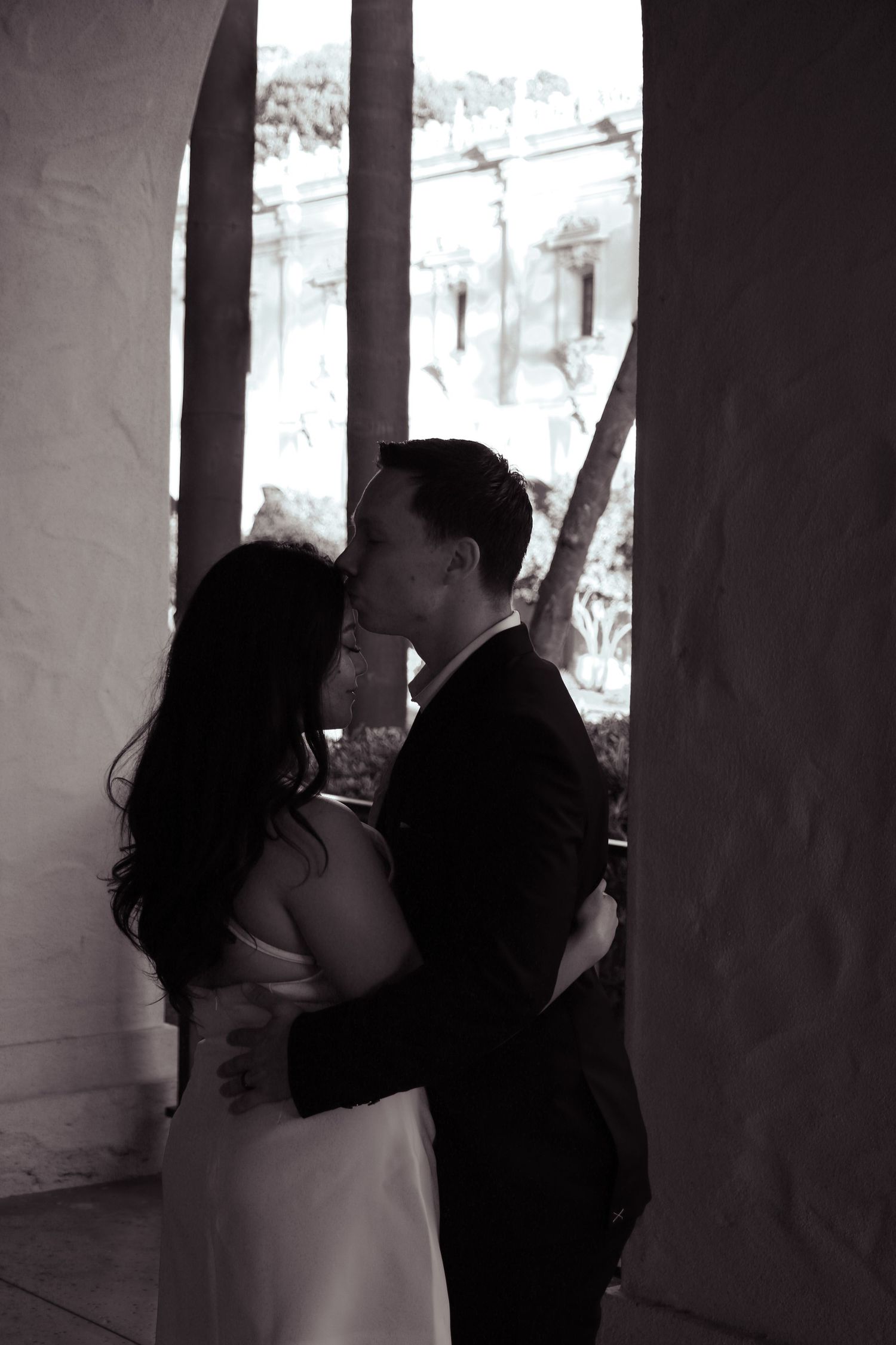 Two figures share a romantic kiss in a shadowy architectural setting creating a silhouetted moment.