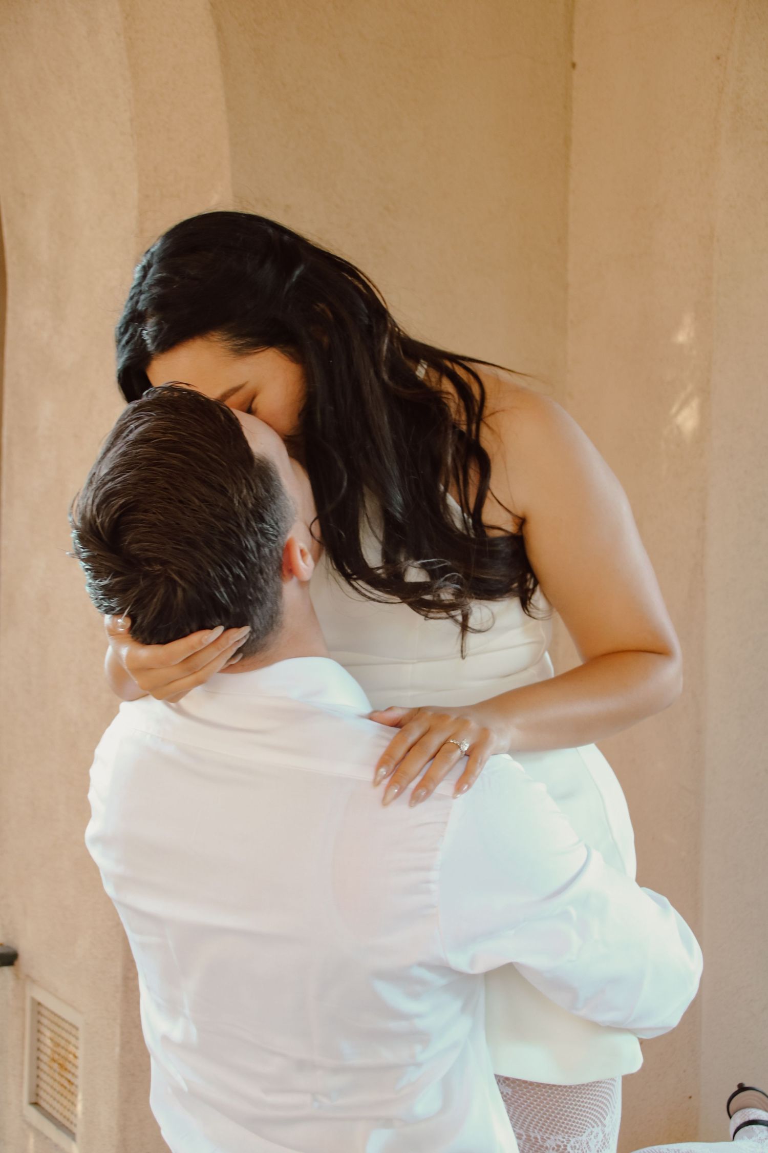Tender moment between couple as they embrace in front of textured wall.