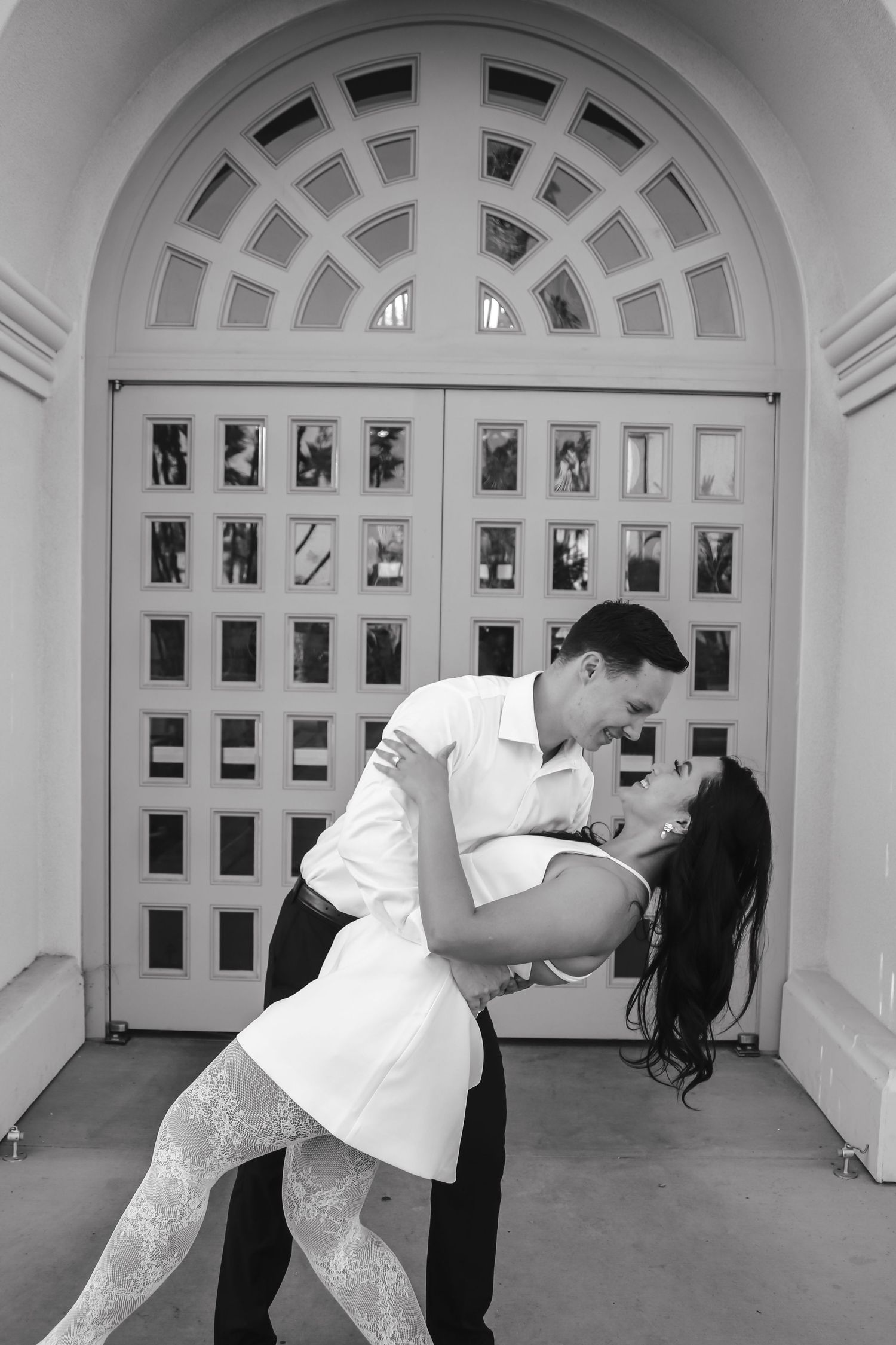 Black and white romantic dip pose captured in front of an architectural doorway.