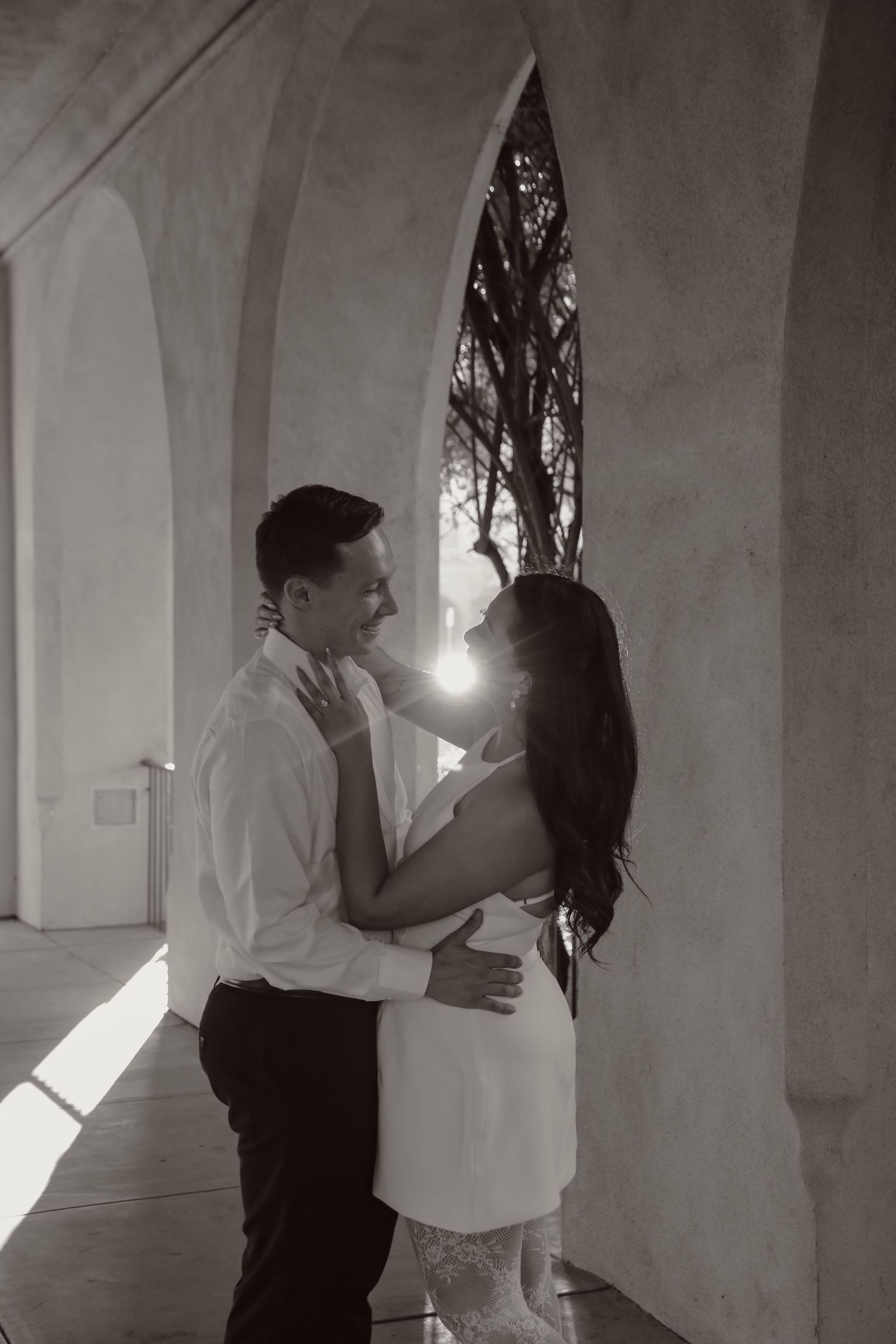 Black and white romantic couple photoshoot in a room with dramatic lighting and architectural elements.
