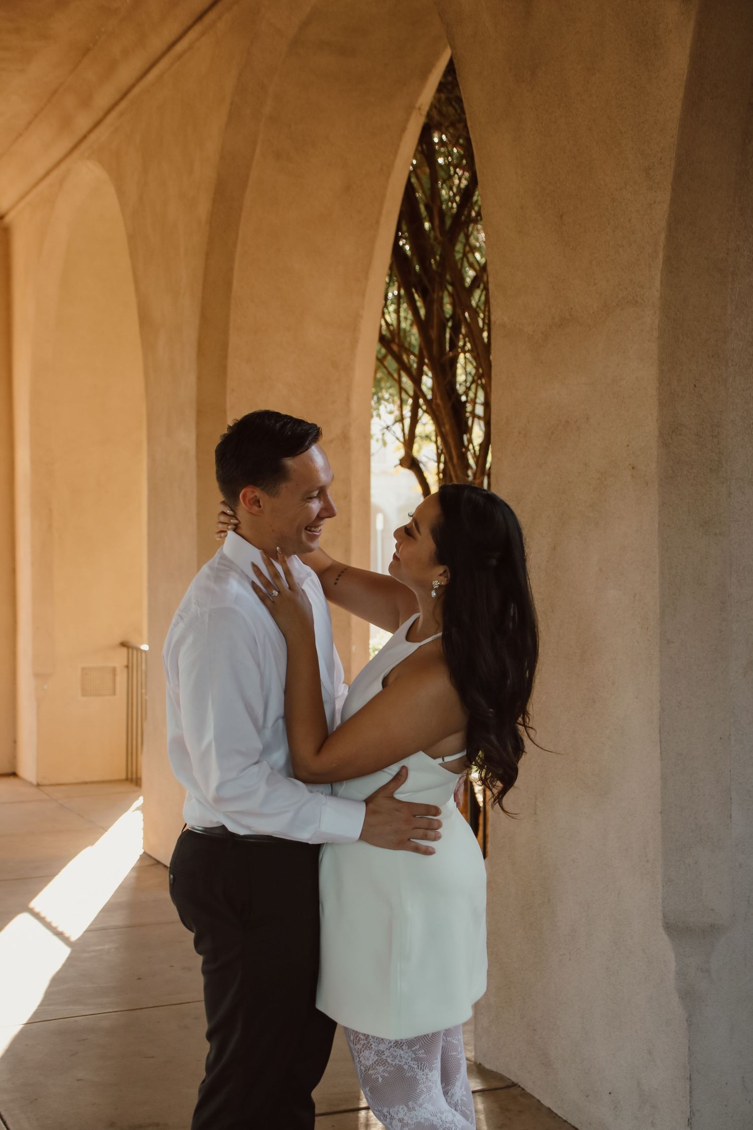 A series of romantic poses between two people in a sun-lit architectural setting.