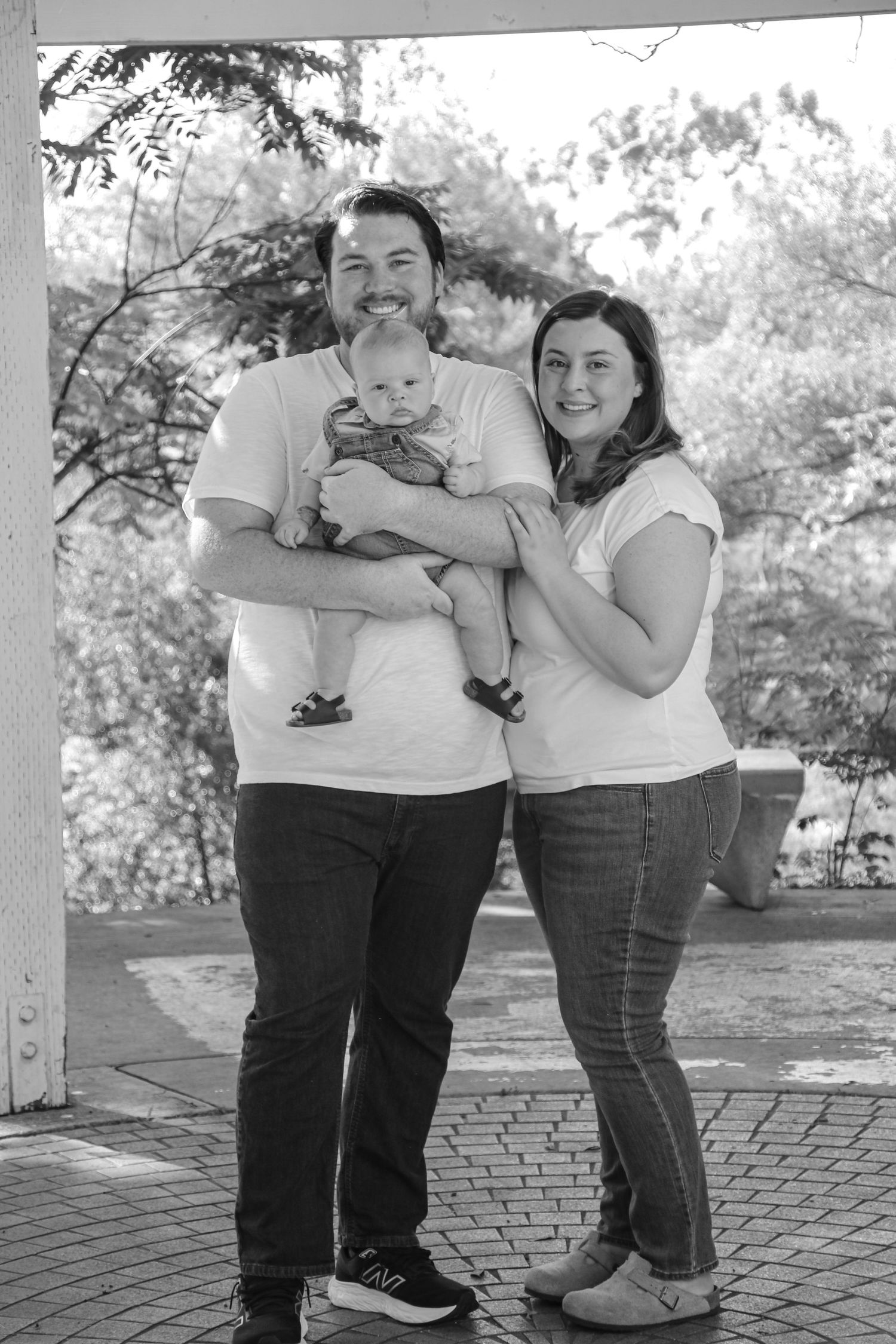 A black and white family portrait taken on a brick patio showing a casual, relaxed moment together.