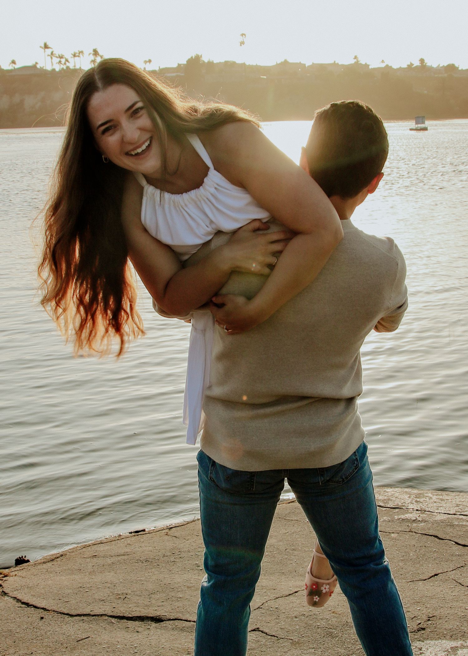 A joyful moment captured between a couple during golden hour by the water.