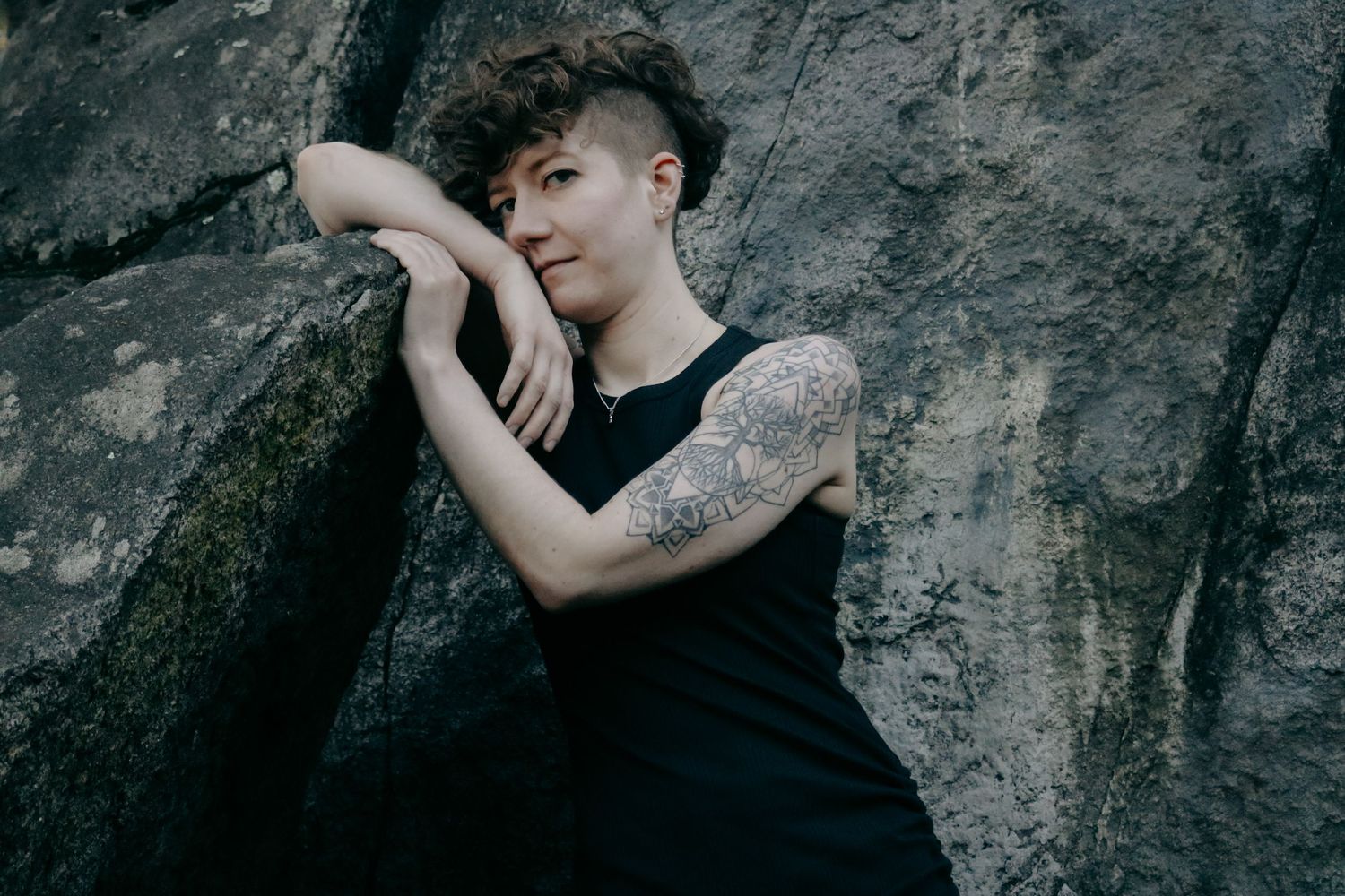 Modern photoshoot of people posing against a textured rock wall background.
