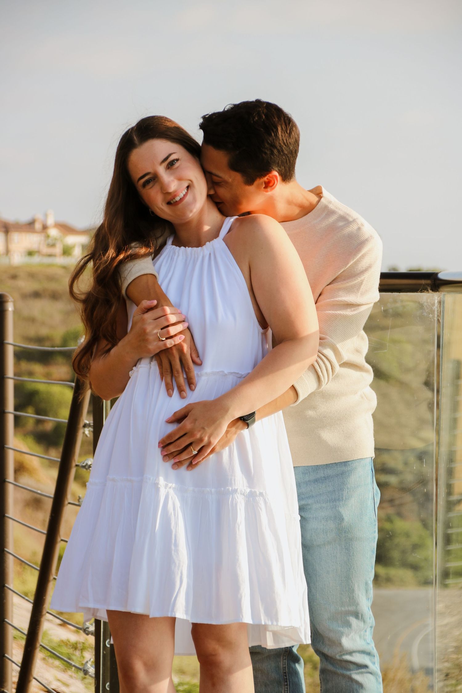 Tender moments between couple in white dress and casual wear against mountain landscape.