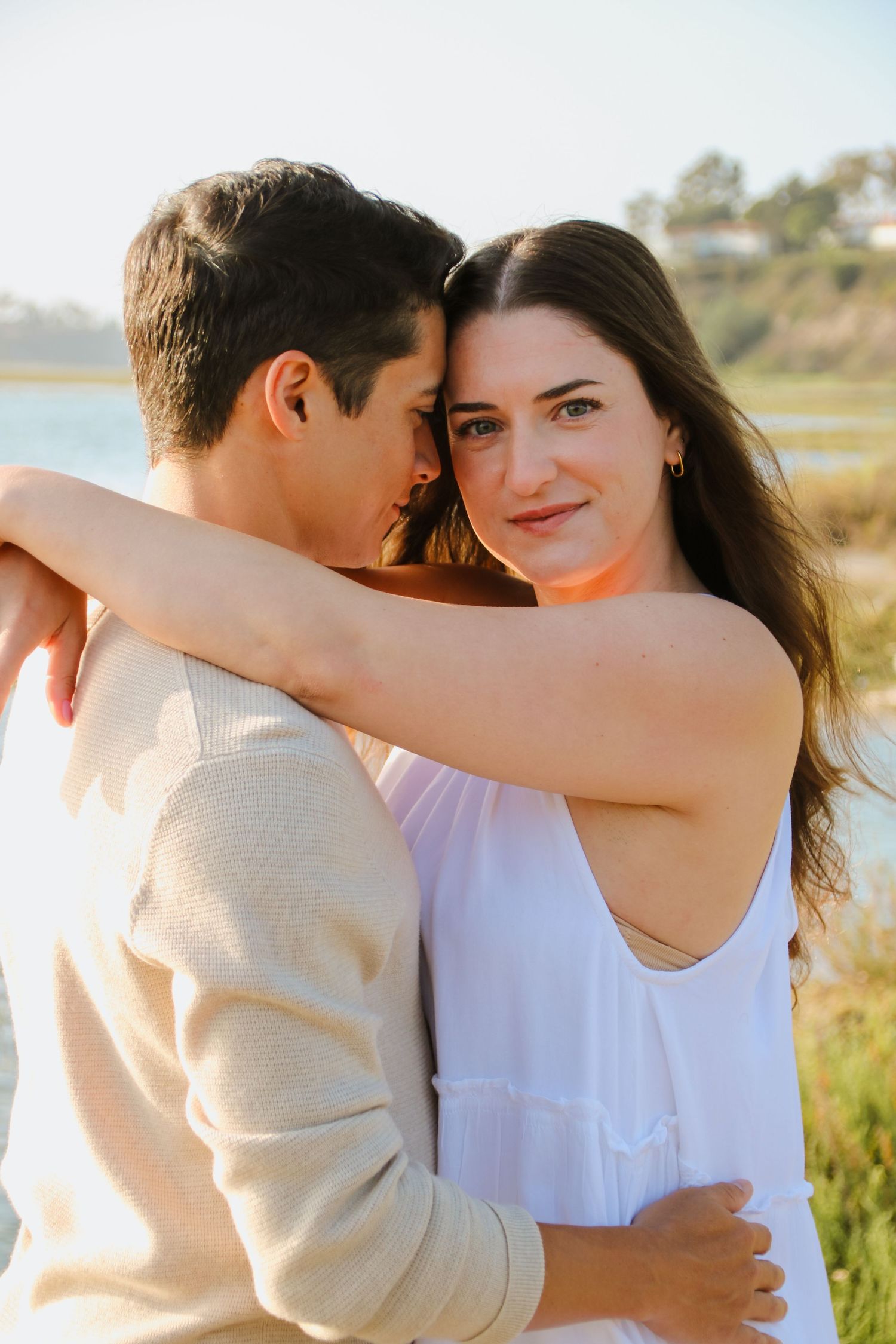 Intimate moment captured between couple during sunset photoshoot by the water.