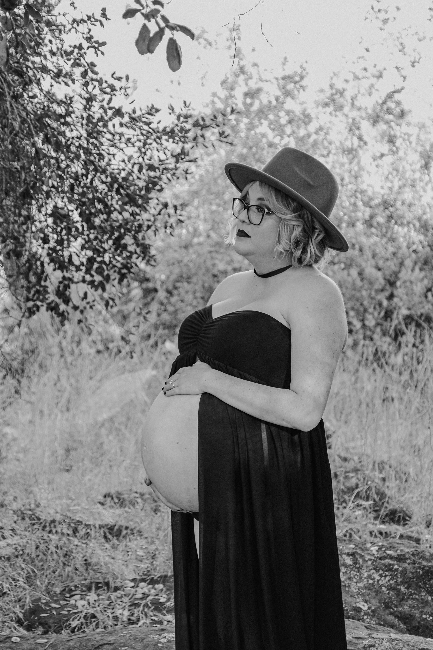 A series of black and white portraits showing someone in a black dress and sun hat against a natural background.
