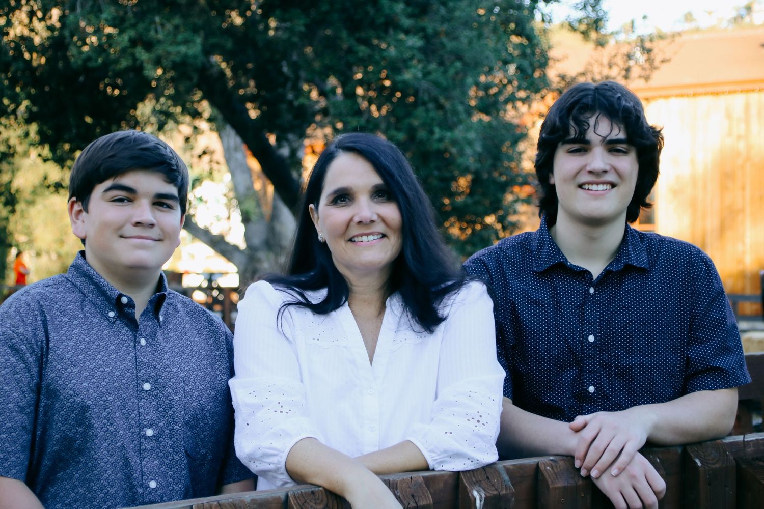 Casual outdoor family photoshoot with everyone arranged in front of trees.