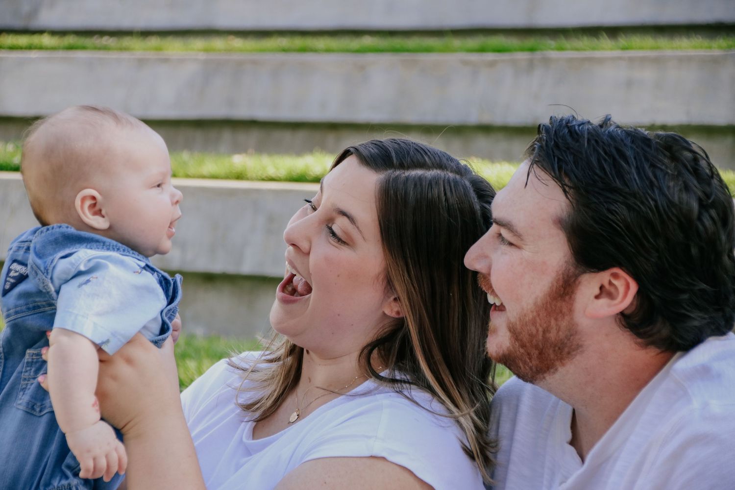 Family shares joyful outdoor moments together while sitting on steps in matching white clothing.