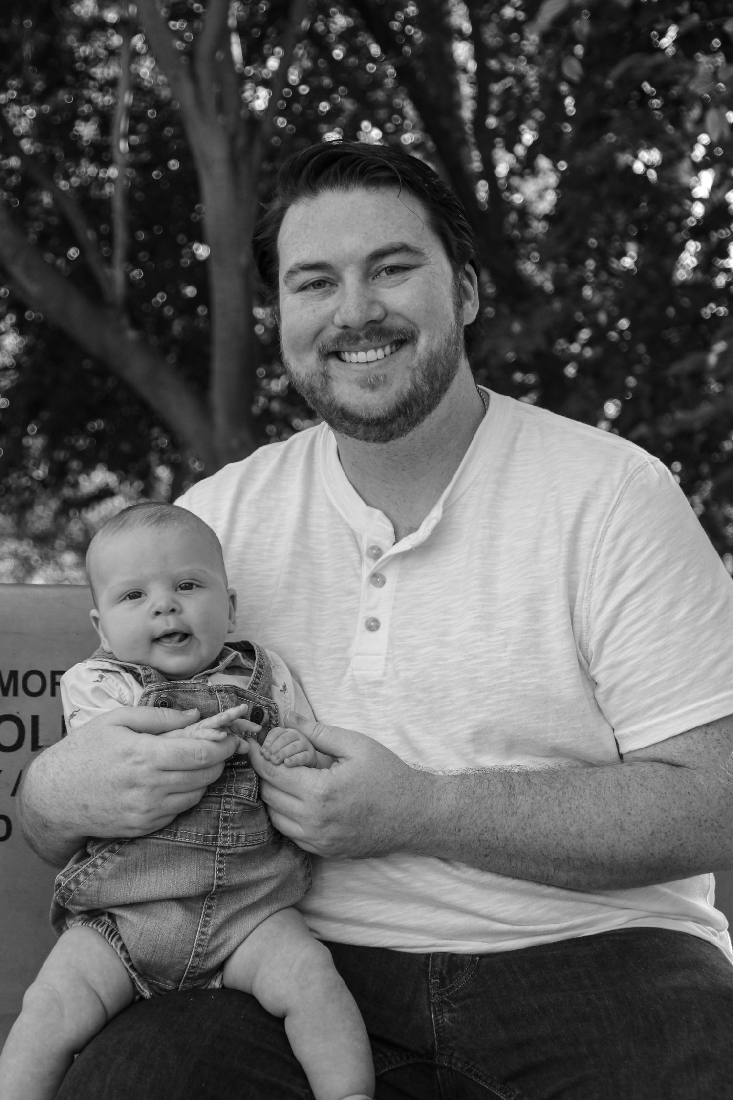 Black and white photos showing tender moments between a father and baby in casual outdoor setting.