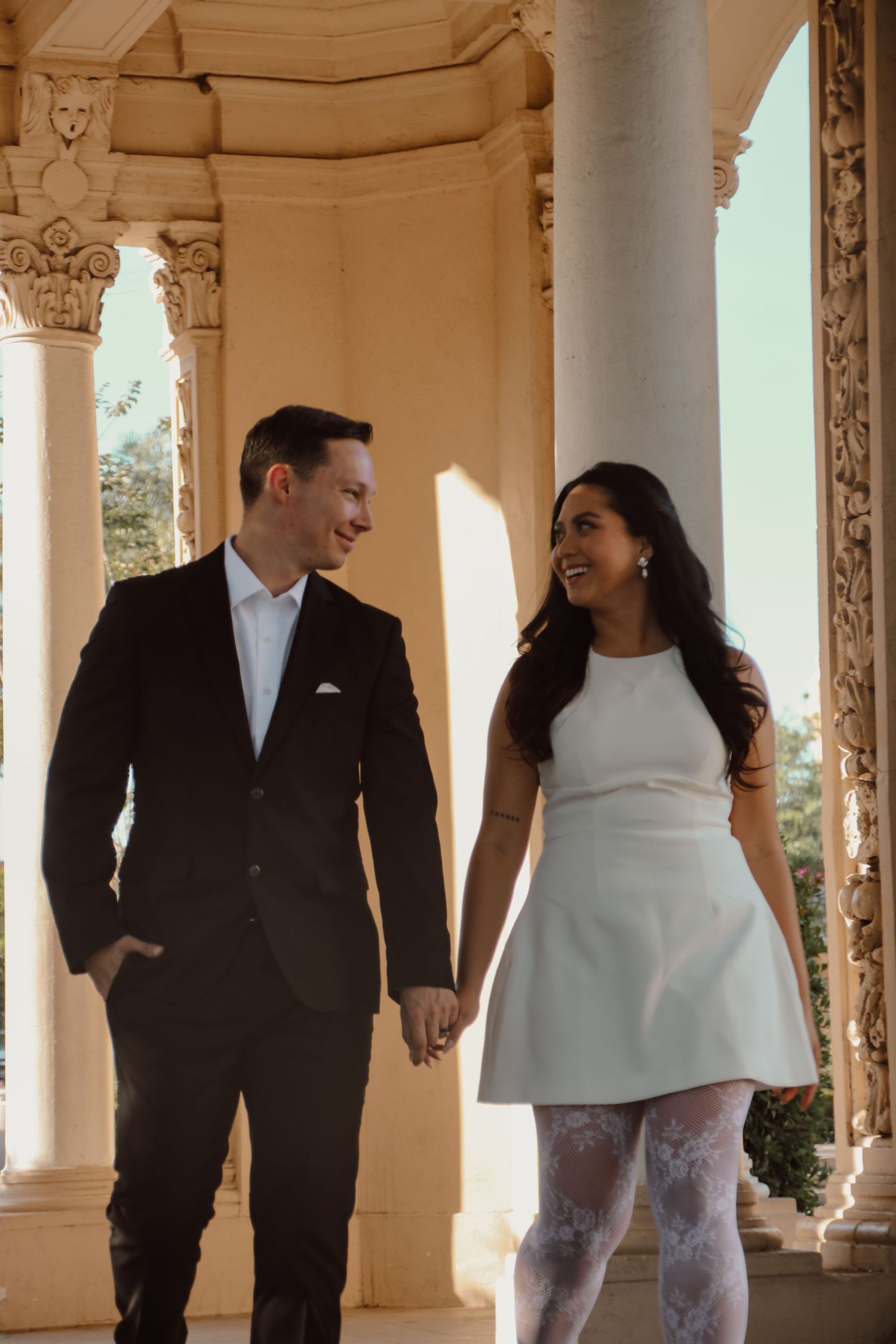 Couple sharing joyful moment while walking through columned walkway.