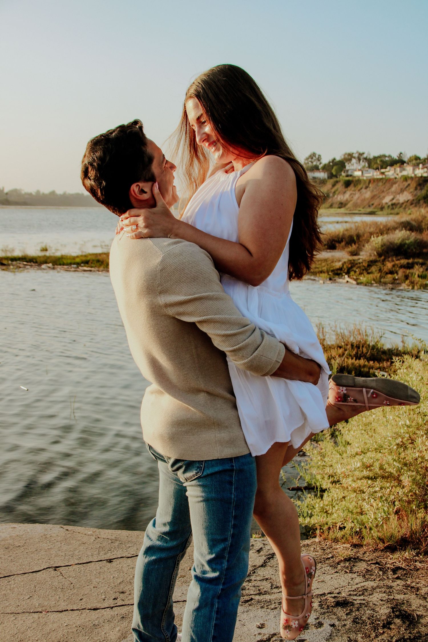 A romantic sunset embrace between a couple on a waterfront path.