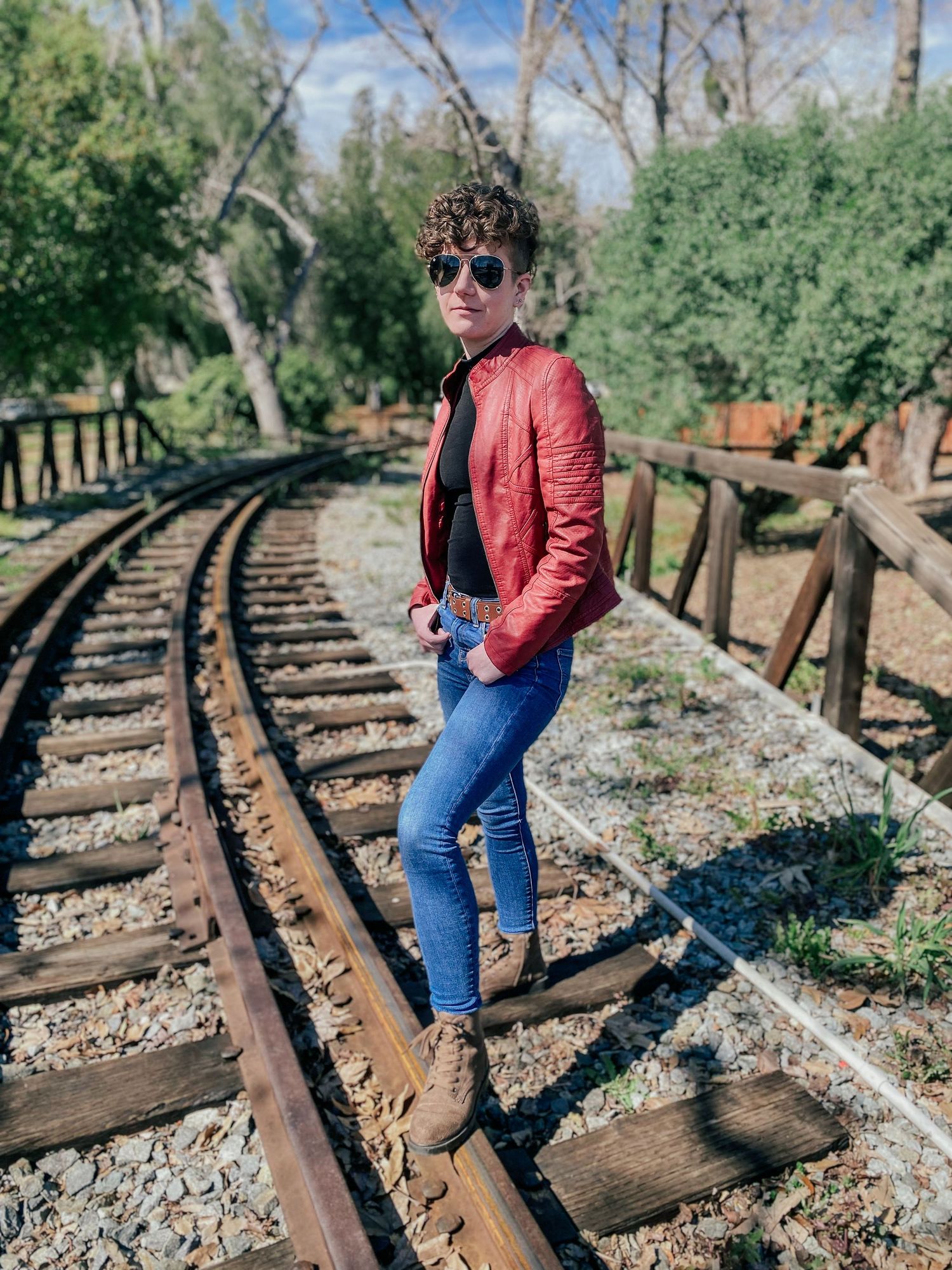 Artistic photoshoot along vintage railway tracks with modern fashion styling.