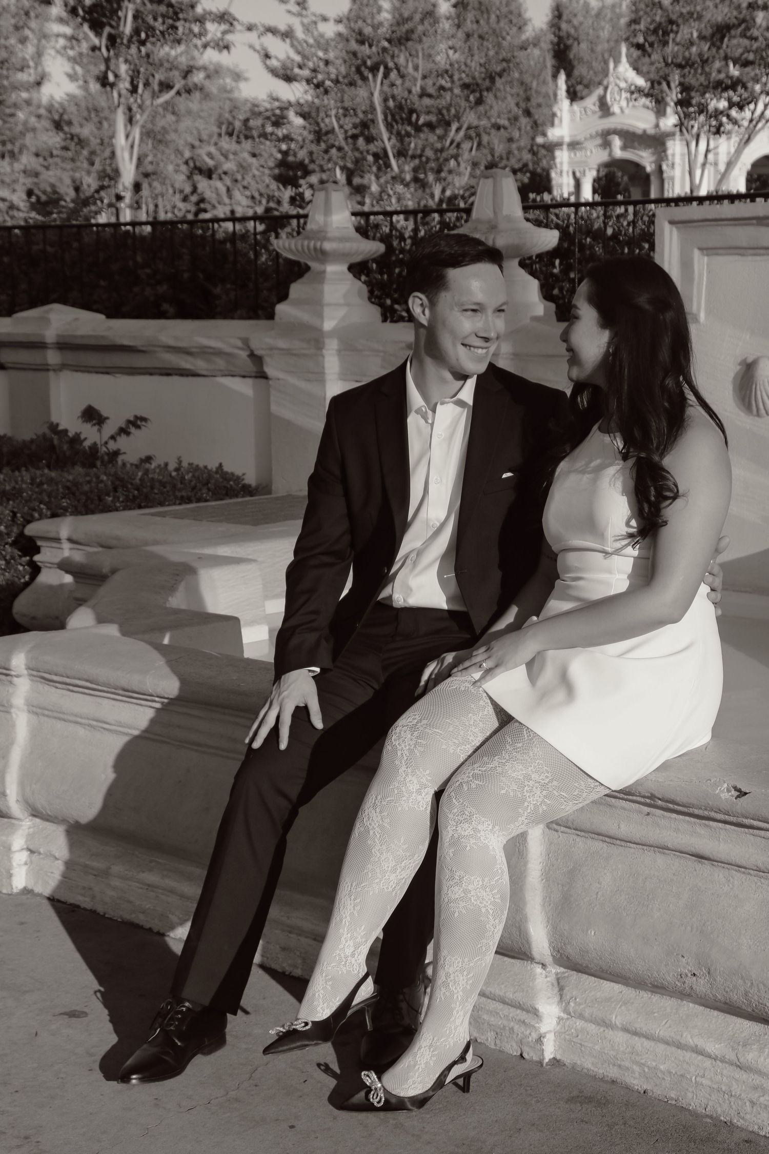 Couple in black and white sharing playful moment on decorative stone steps.