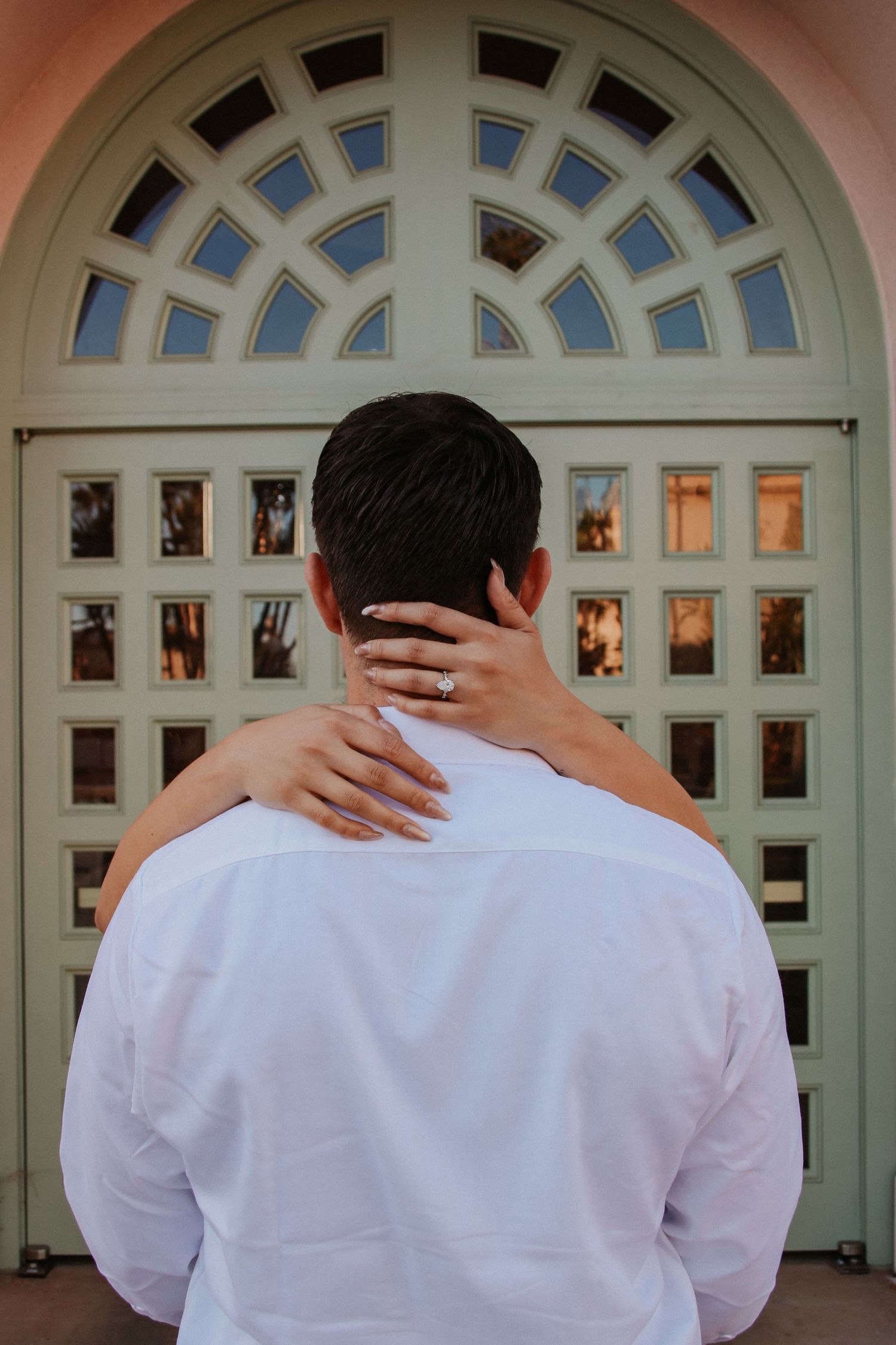 Back view of a person in white shirt against an architectural door with geometric patterns.