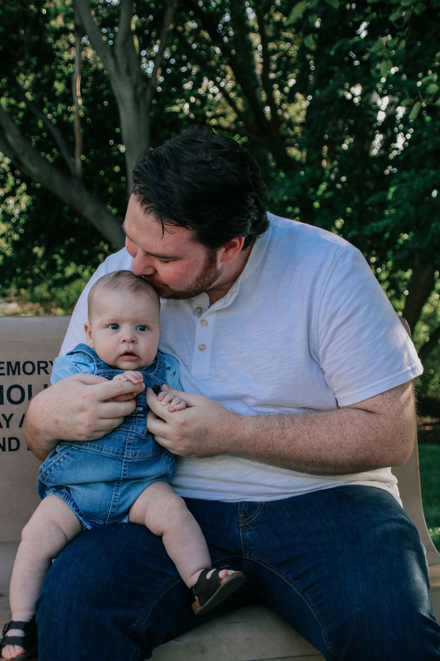 Gentle interaction between father and infant during outdoor photo session.