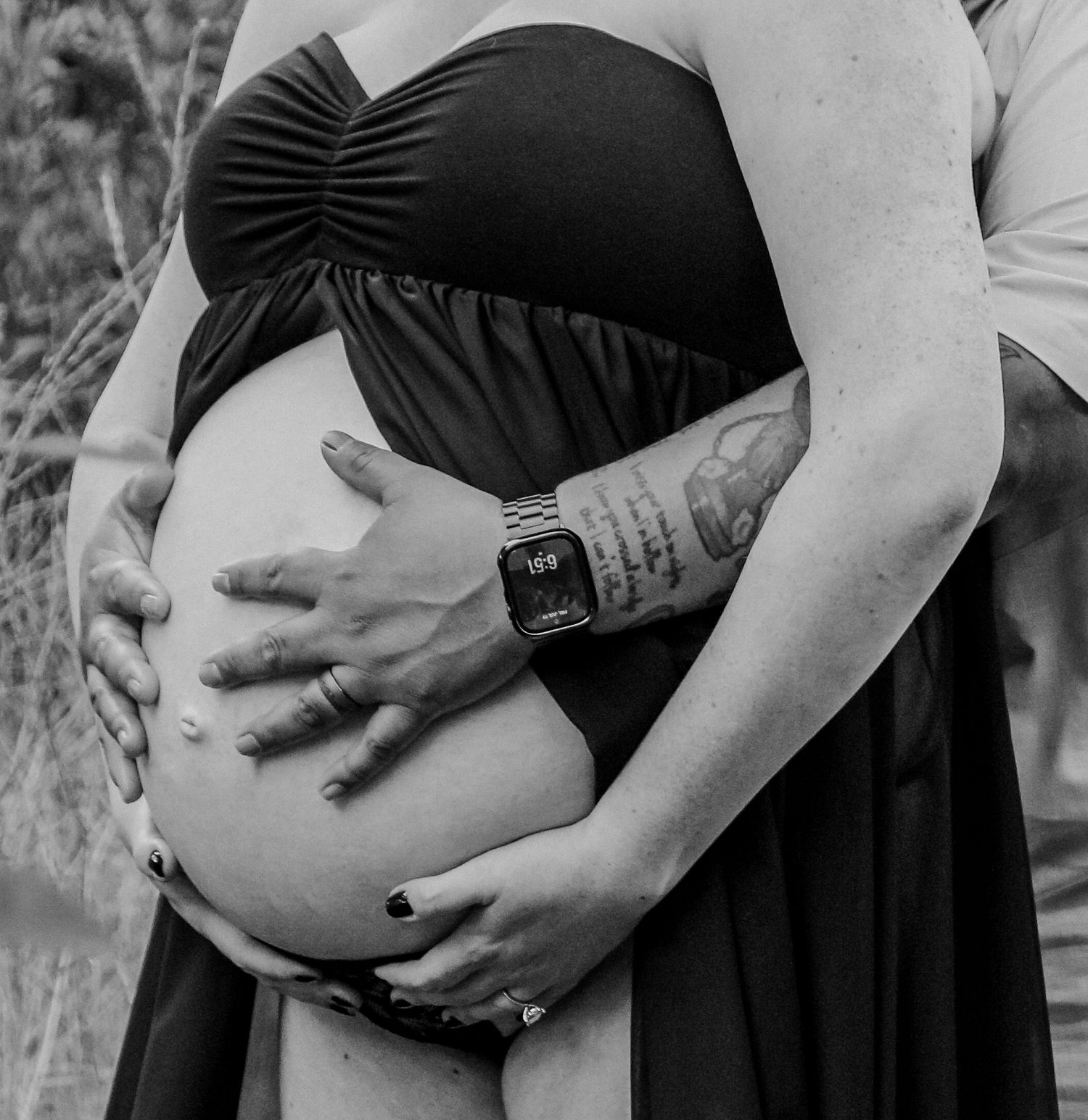 Black and white maternity photo series showing close-up views of pregnant belly being cradled by hands.