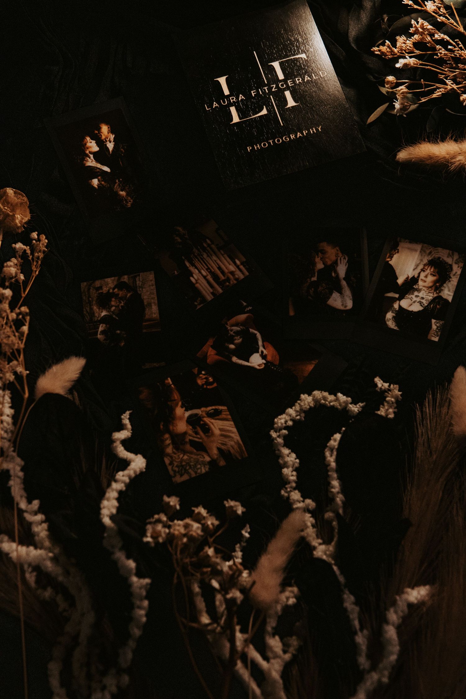 Dark moody flat lay of wedding photos and dried flowers on black background.
