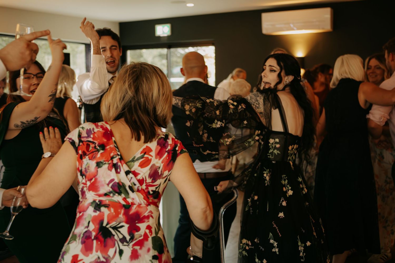 Guests dancing and celebrating at a lively wedding reception party indoors.