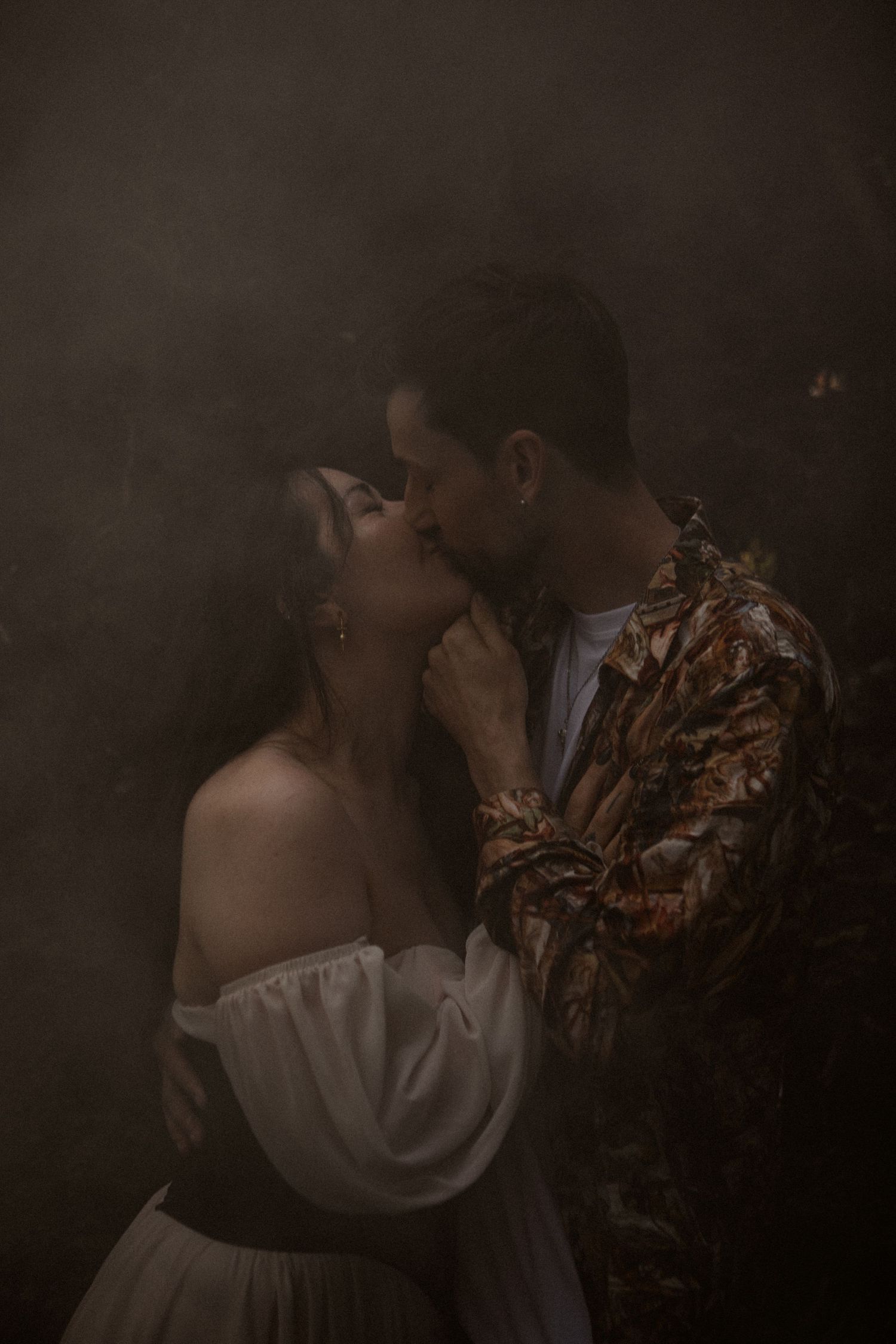 A moody portrait captures an intimate moment between two people in vintage-inspired clothing.