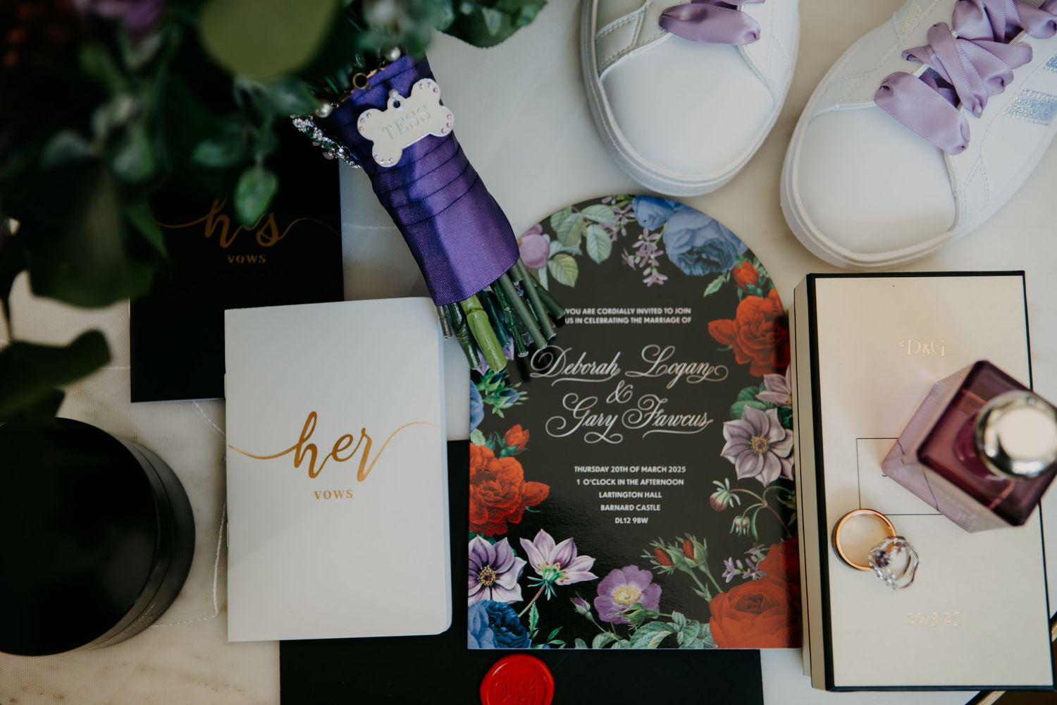 Elegant wedding flat lay featuring floral invitation suite, gold rings, white sneakers, and a personalized her journal on white surface.