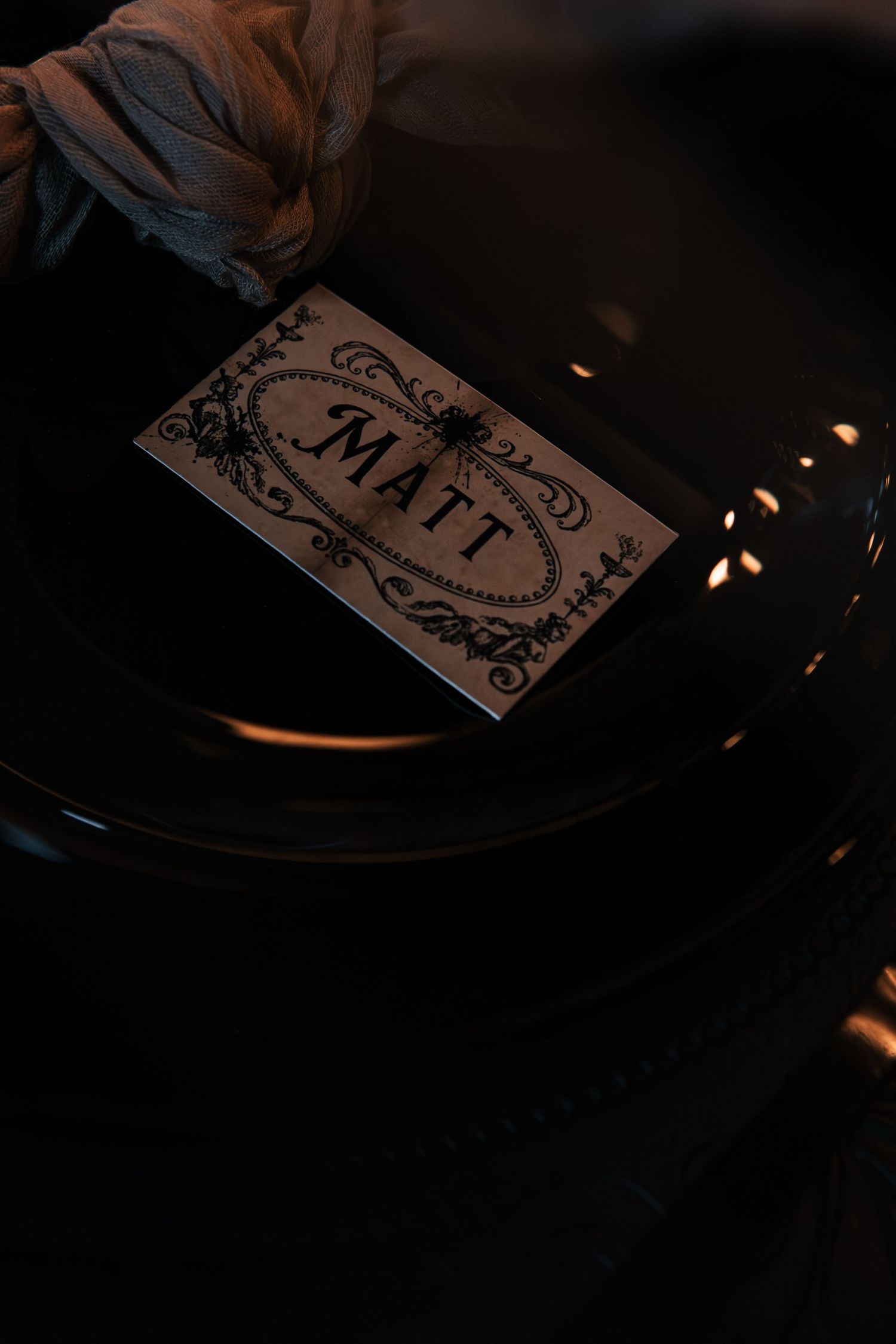 Elegant gothic wedding place card for Matt with ornate black decorative border on dark plate setting.